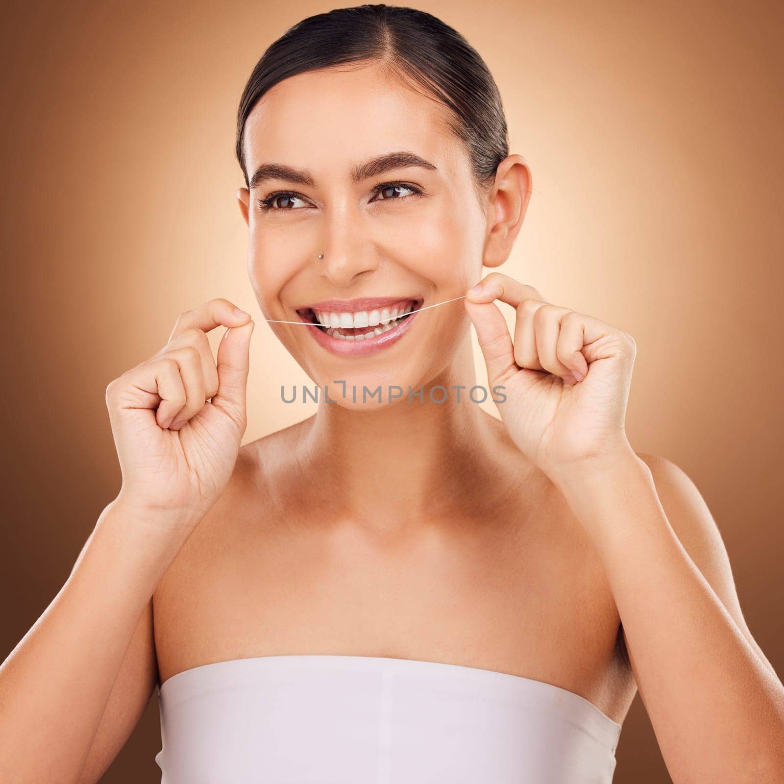 Dental floss, face and happy woman cleaning teeth for oral hygiene routine, self care flossing or tooth healthcare. Mouth plaque treatment, gum care smile and studio female beauty on brown background by YuriArcurs