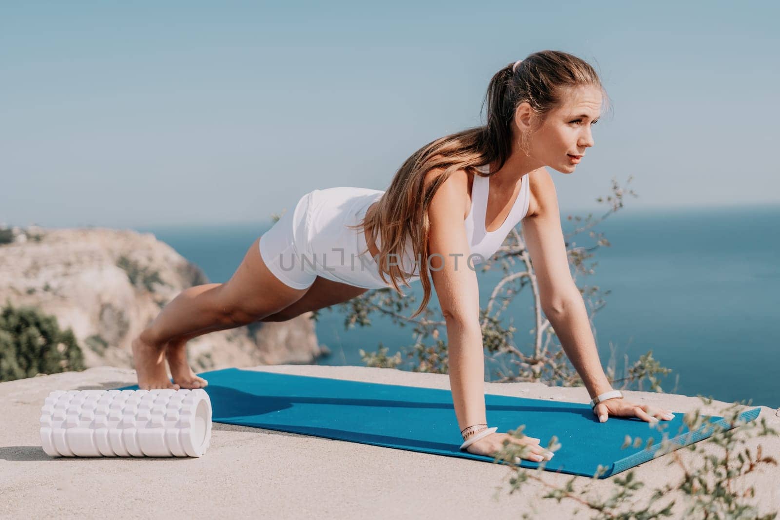 Fitness woman sea. Outdoor workout with fitness rubber bands in park over beach. Female fitness pilates yoga routine concept. Healthy lifestyle. Happy fit woman exercising with rubber band in park