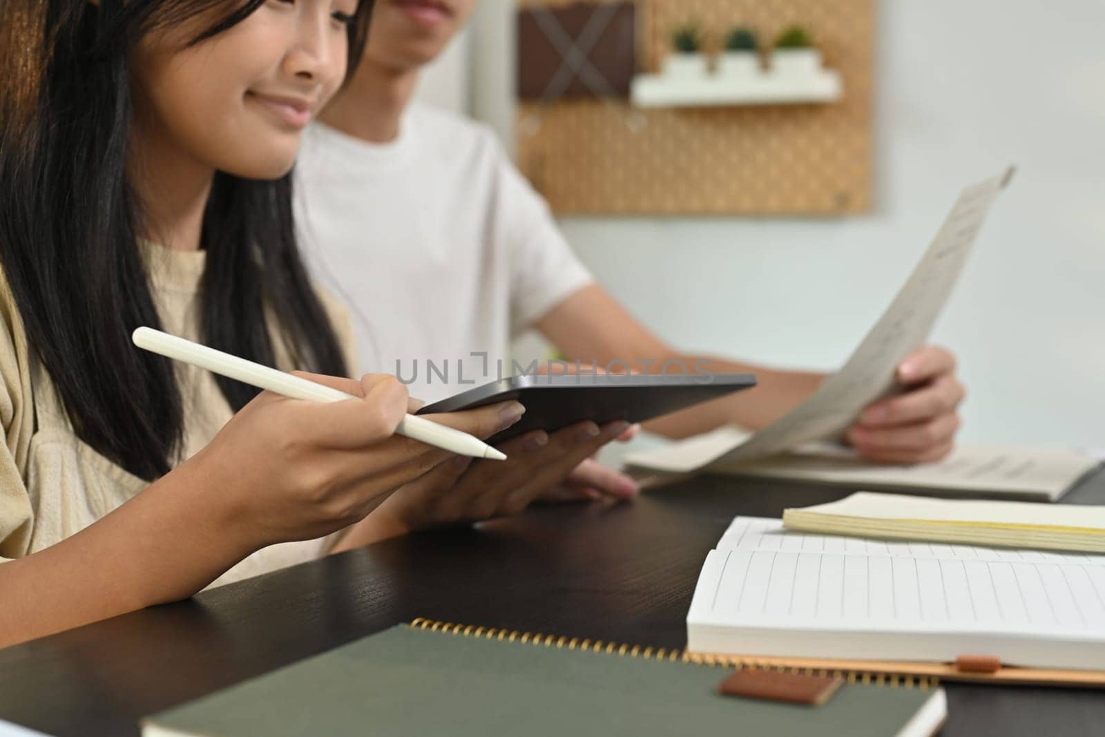 Cropped shot of teenage student learning, doing homework with tutor at home. Education and homeschooling concept.