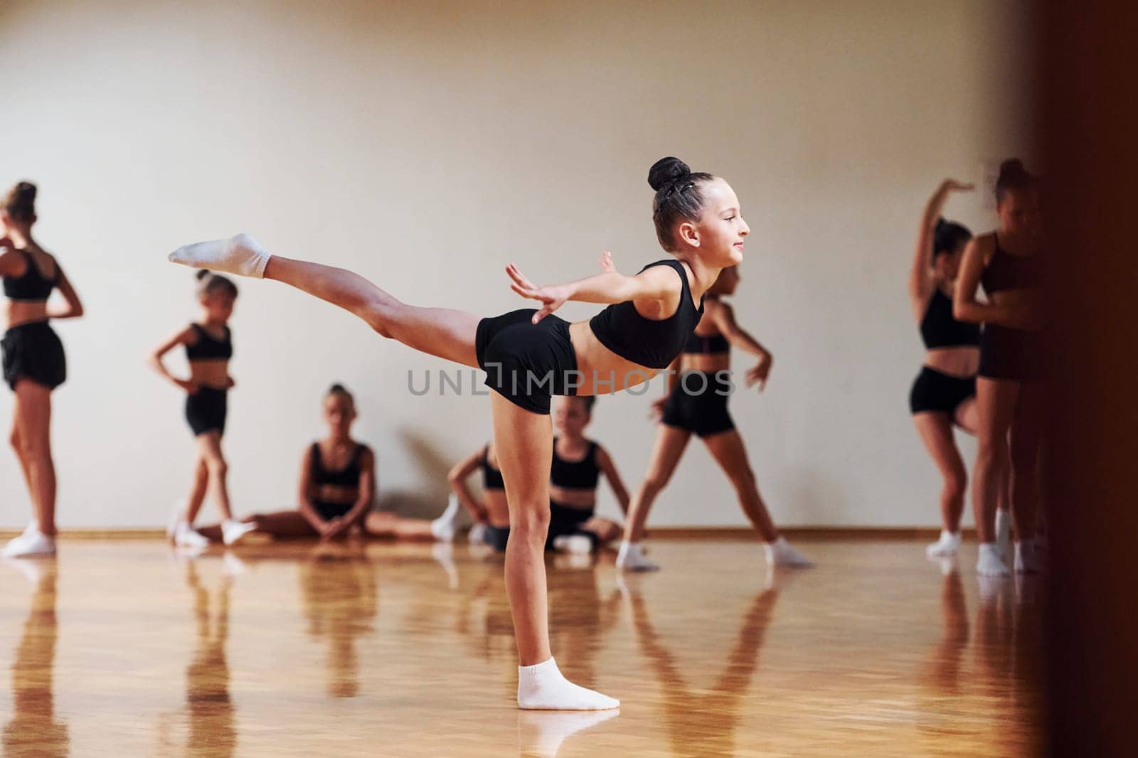 Group of female kids practicing athletic exercises together indoors by Standret