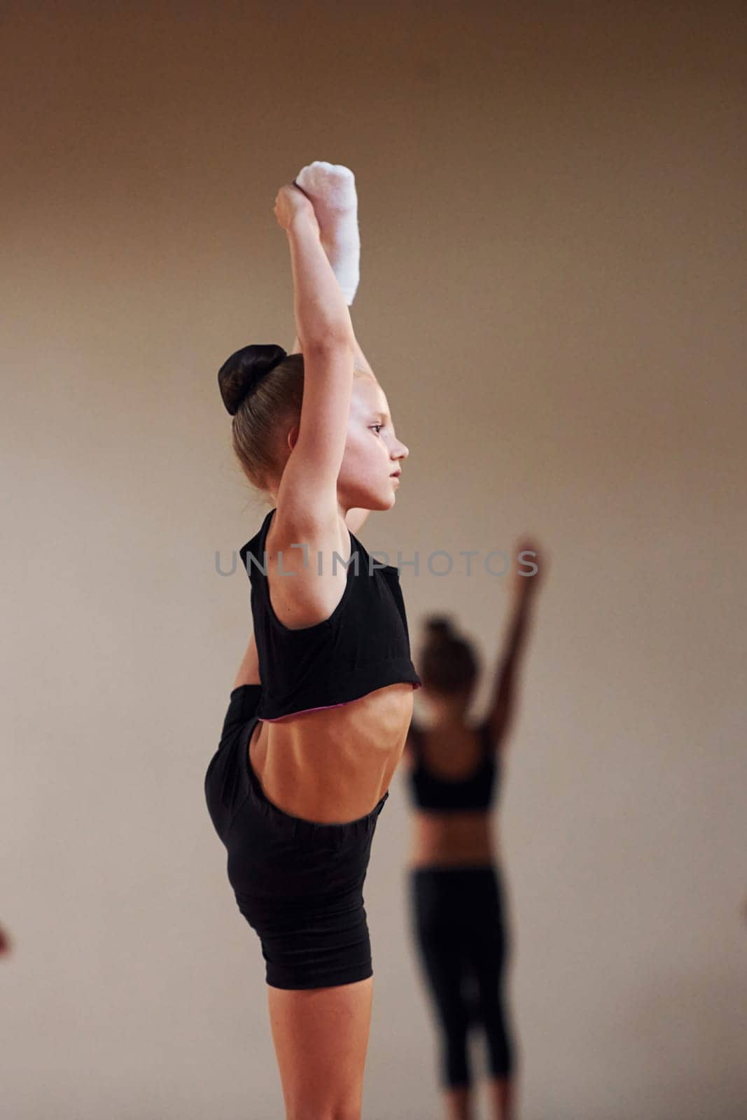 Group of female kids practicing athletic exercises together indoors by Standret