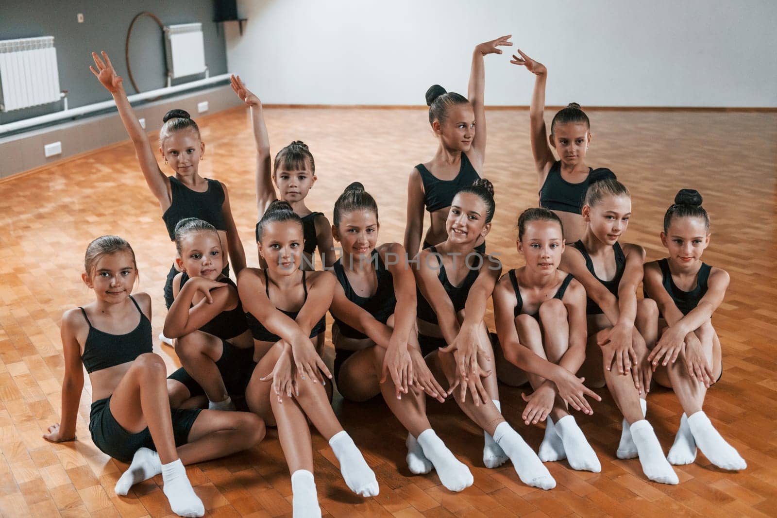 Posing for a camera. Group of female kids practicing athletic exercises together indoors by Standret