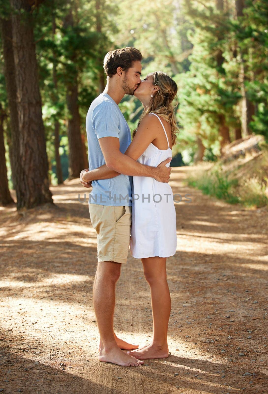 Couple kiss, love and hug in forest, summer with freedom and adventure, relationship with affection and care outdoor. People together in nature park, commitment and trust with romance and bonding.