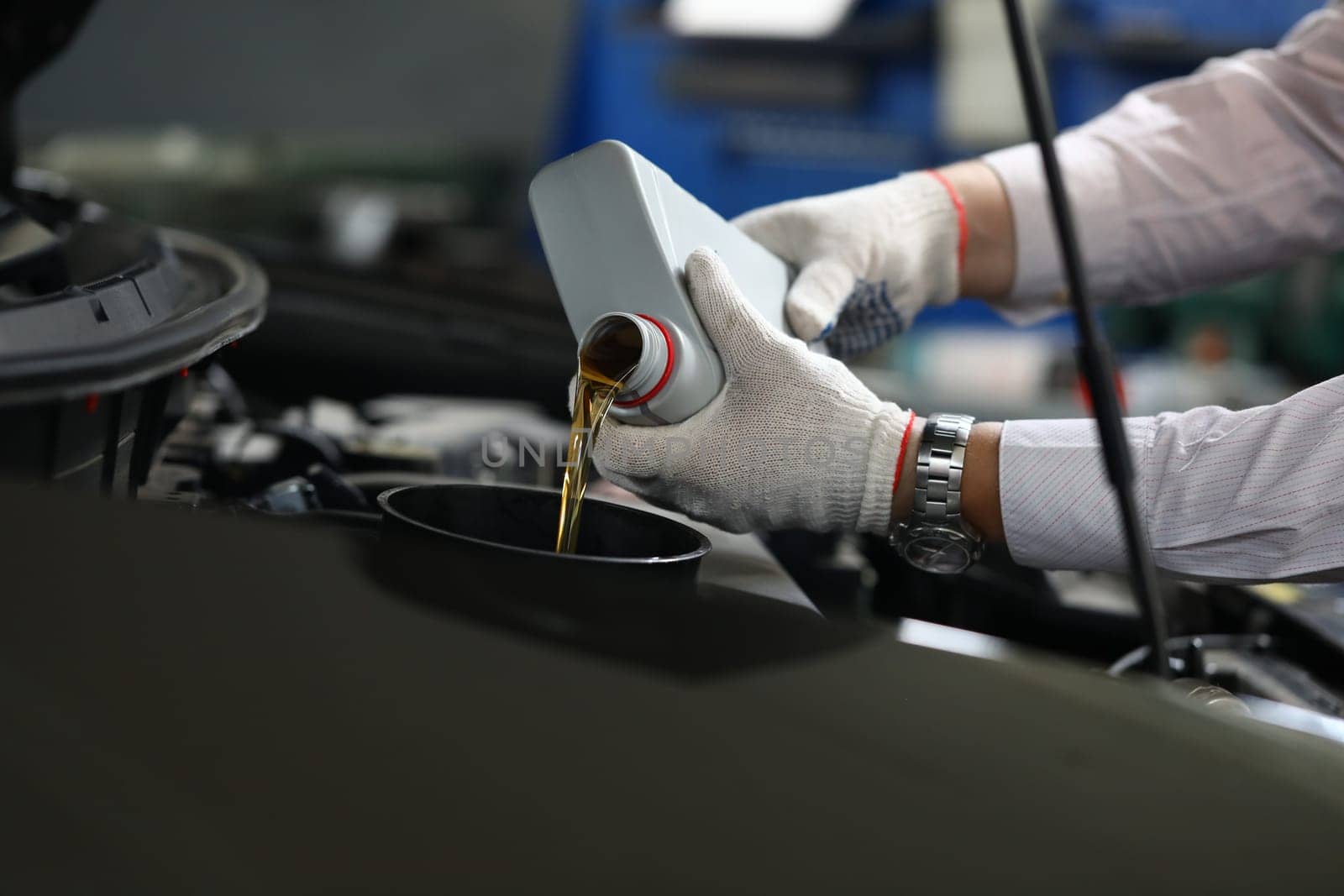 Closeup of experienced mechanic checking and pouring oil into special hole in car by kuprevich