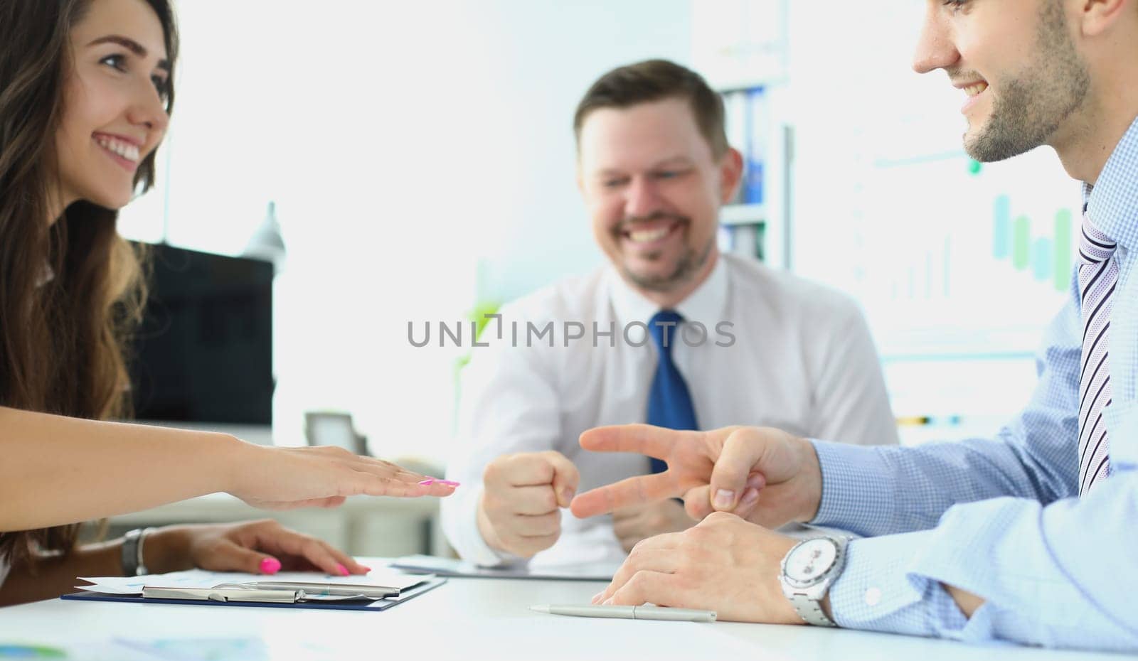 Caucasian businessman and businesswoman playing Rock Paper Scissors with business people by kuprevich