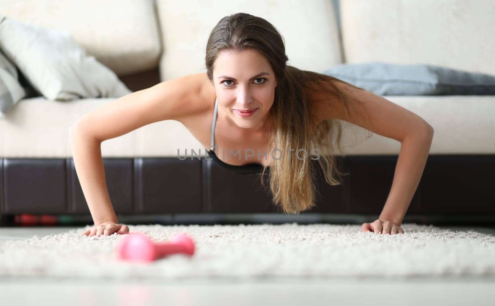 Young beautiful sports girl doing exercises at home on couch by kuprevich