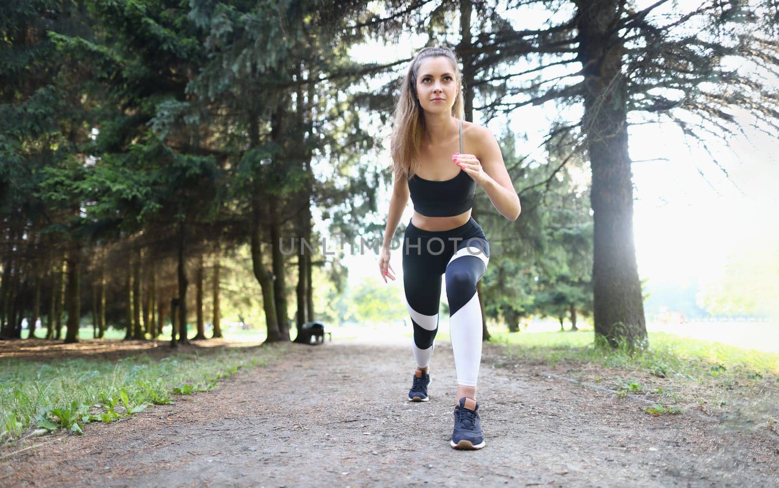 Beautiful athletic young woman starts jogging in park. Morning or evening run concept