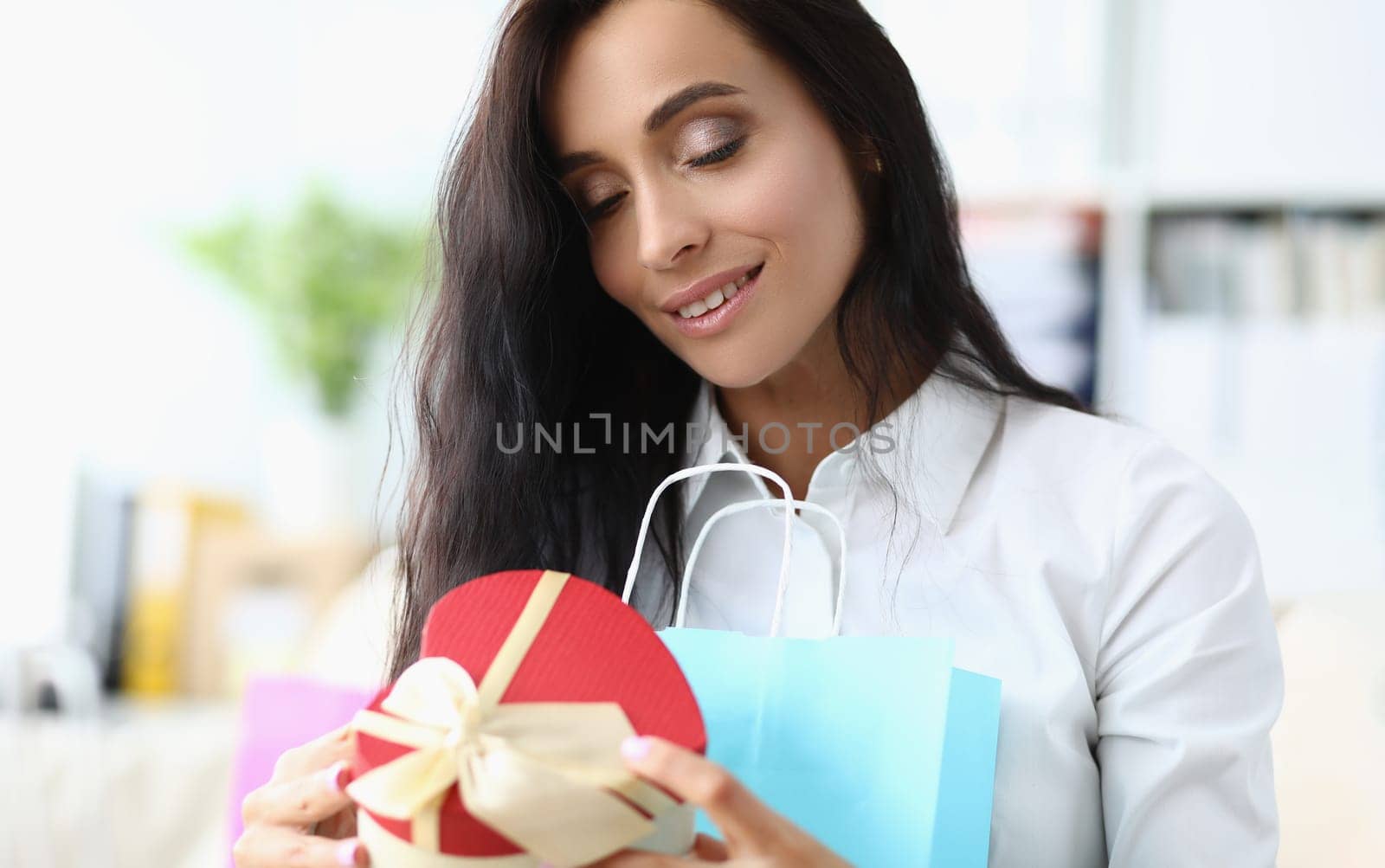 Beautiful young woman enjoys gift. Woman holding gift box concept
