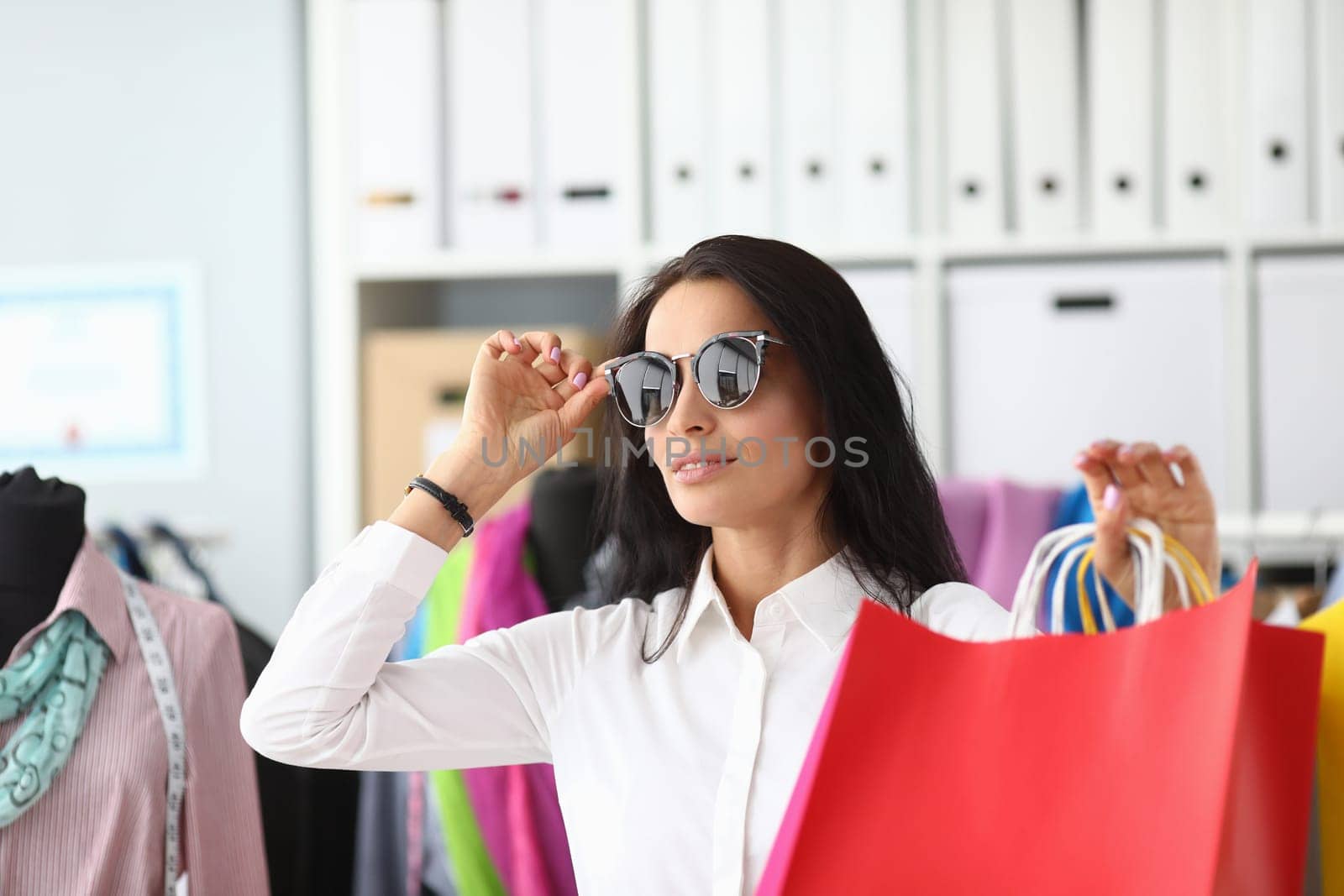 Stylish woman in sunglasses holding shopping bags by kuprevich