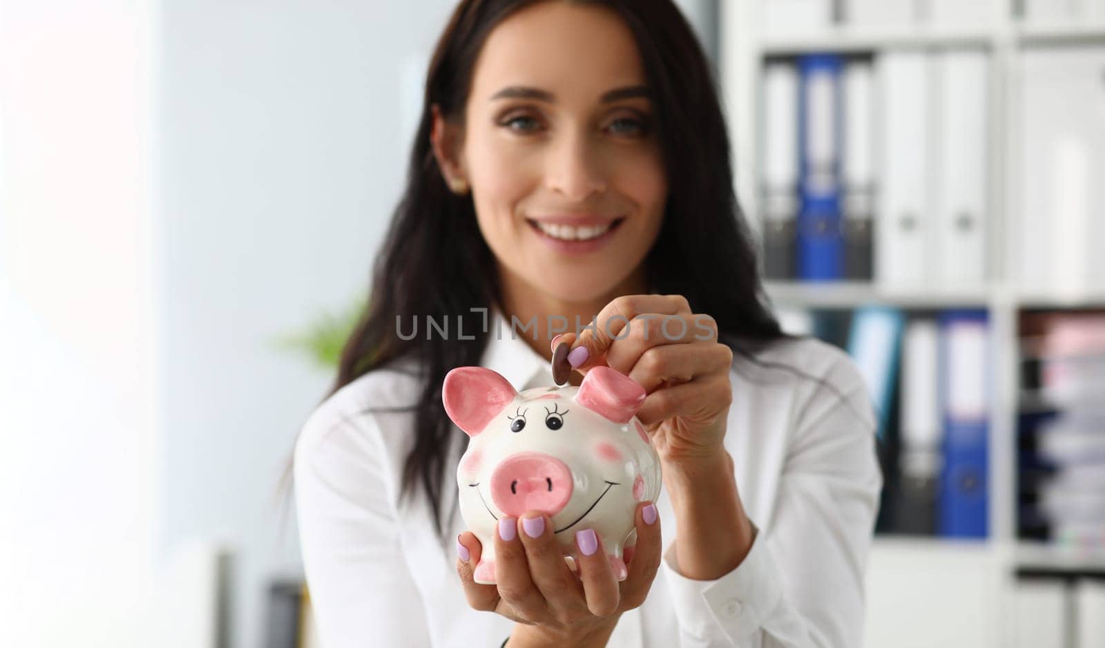 Beautiful smiling woman throws a coin into piggy bank. Accumulation of financial investments and and family savings concept