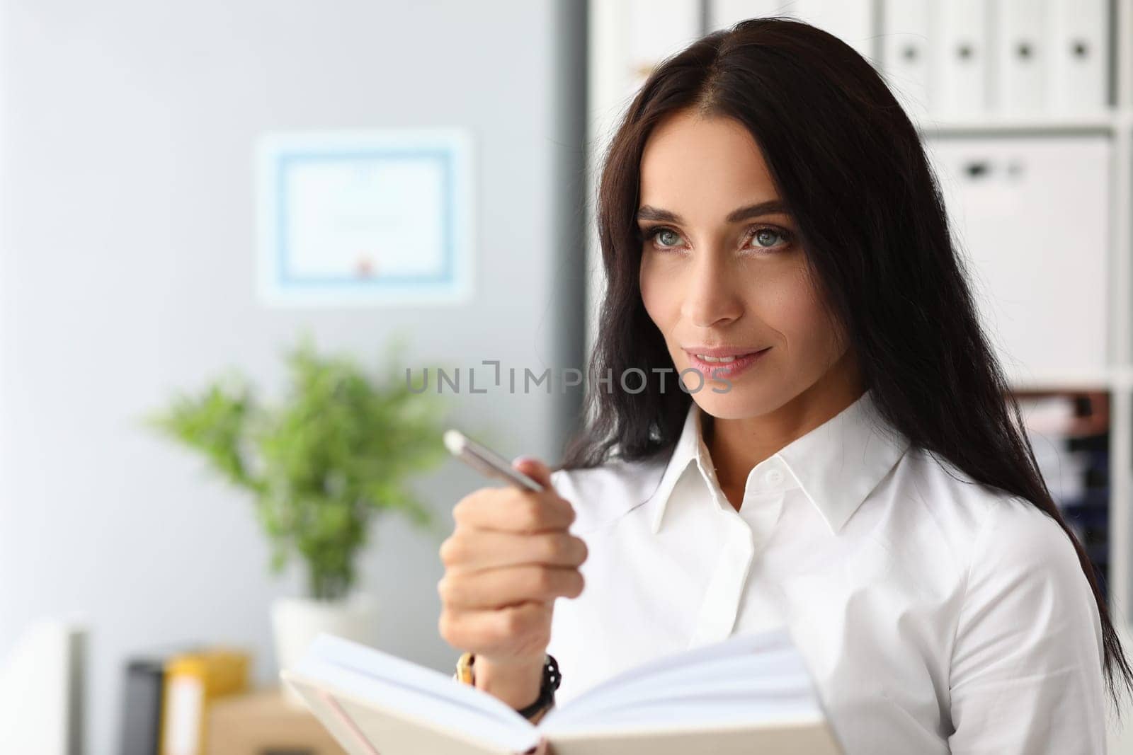 Portrait of a pensive beautiful businesswoman with pen and diary by kuprevich