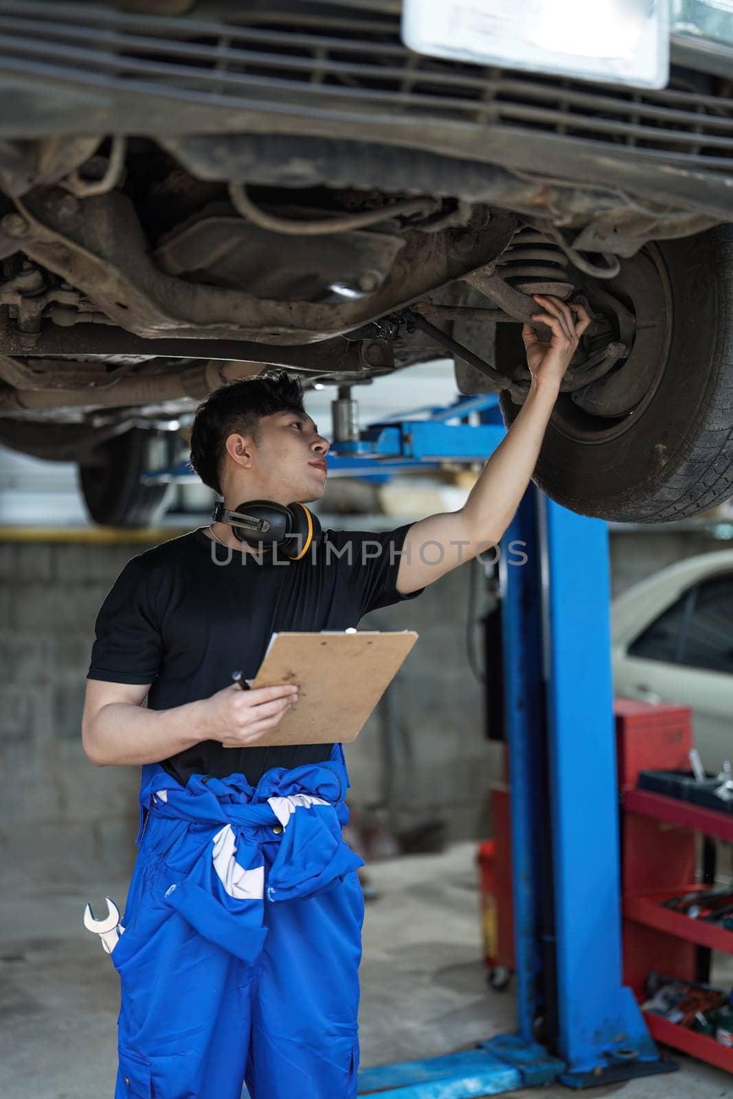 car service, repair, maintenance and people concept - happy smiling auto mechanic man or smith with clipboard at workshop by wichayada