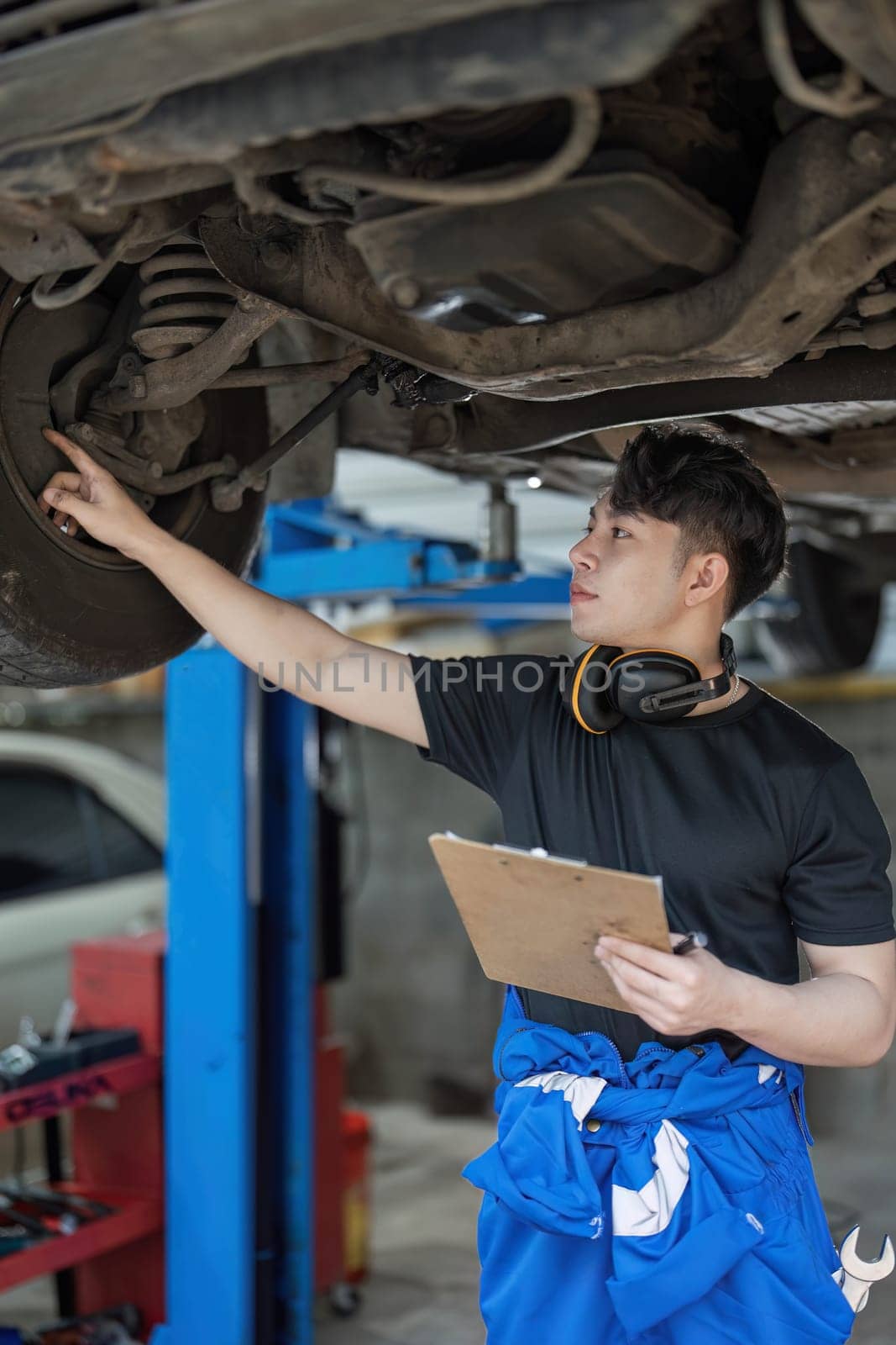 car service, repair, maintenance and people concept - happy smiling auto mechanic man or smith with clipboard at workshop by wichayada