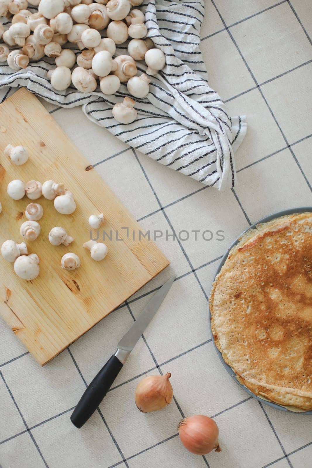 cutting raw mushrooms at table in kitchen. Homemade pancakes. Breakfast or dinner, cooking at home