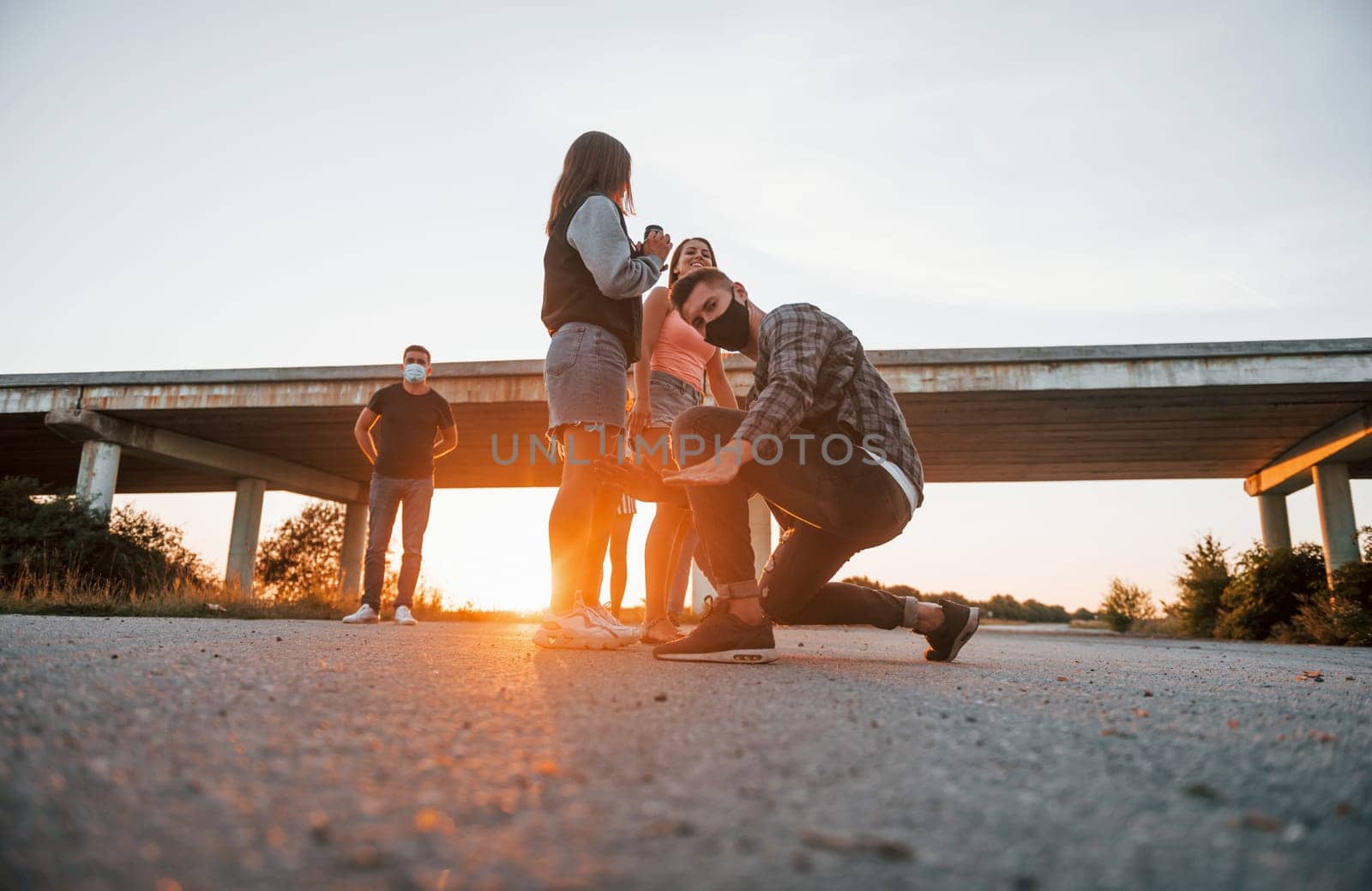 Walking on the road. Group of young cheerful friends having fun together. Party outdoors.