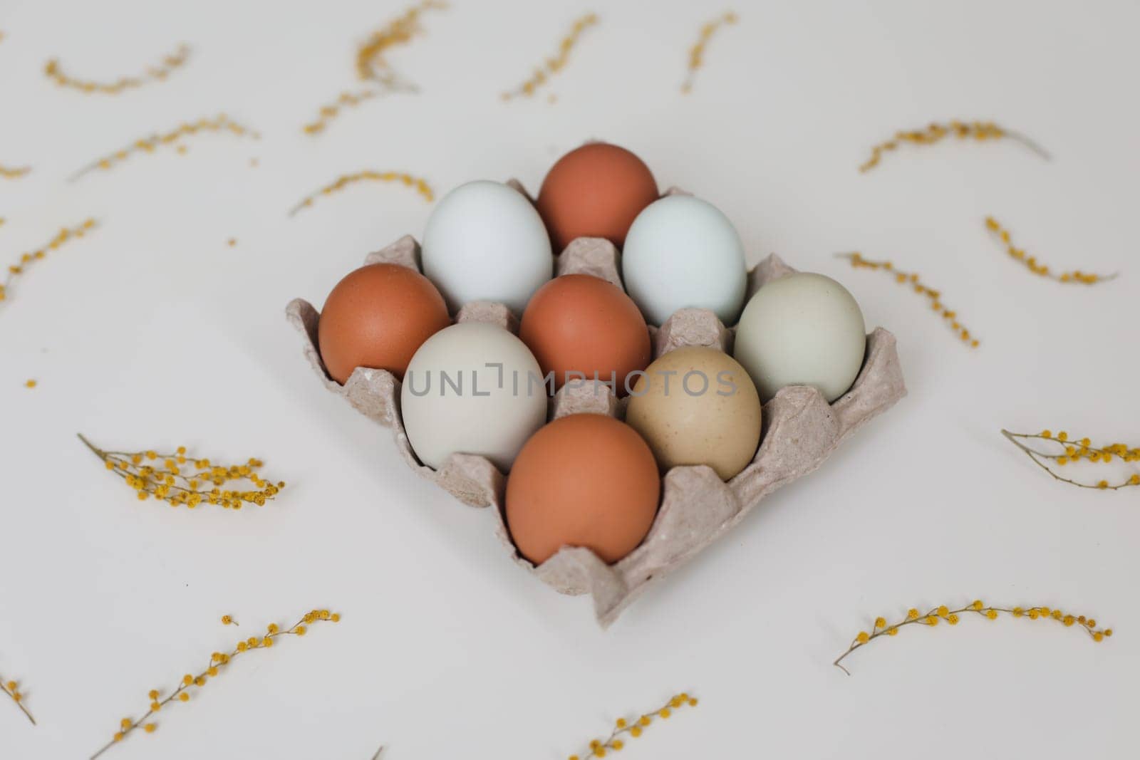 fresh chicken eggs of natural shades and colors in a recycled box on a white background.