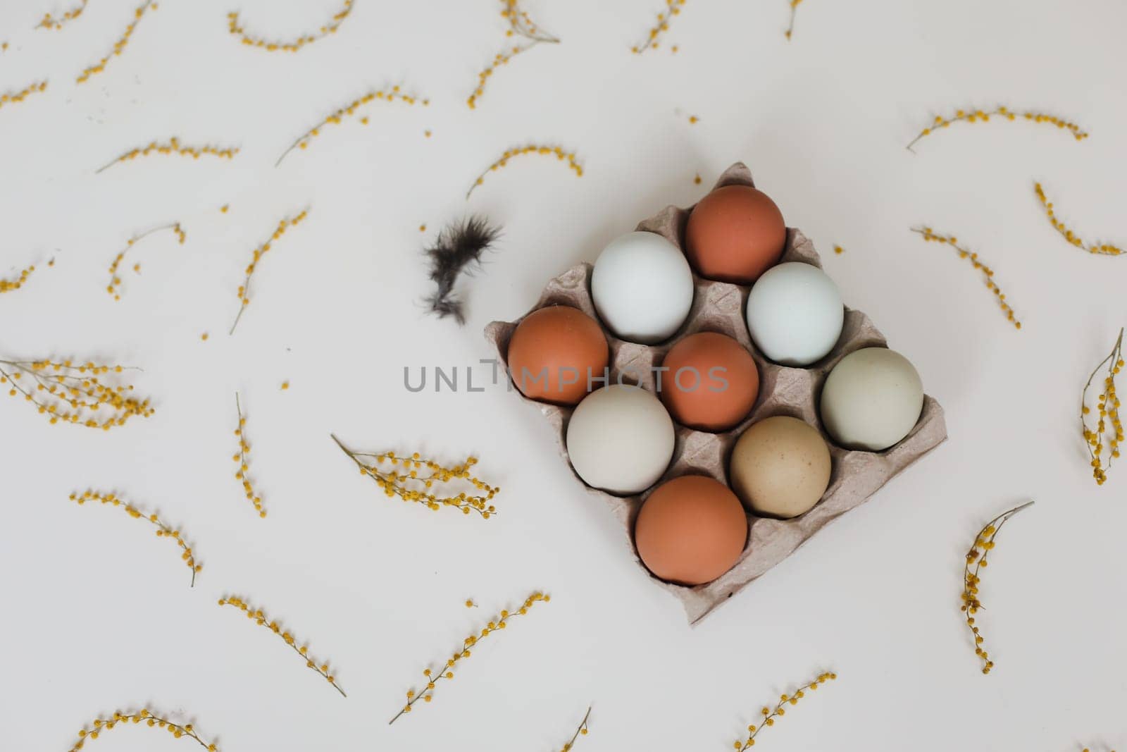 fresh chicken eggs of natural shades and colors in a recycled box on a white background.
