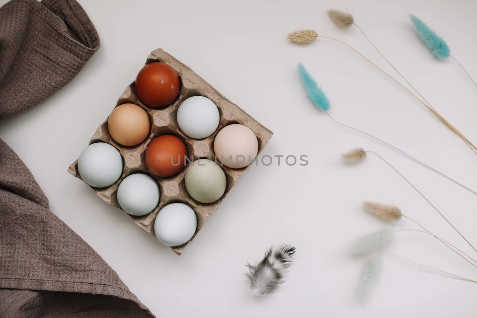 fresh chicken eggs of natural shades and colors in a recycled box on a white background.