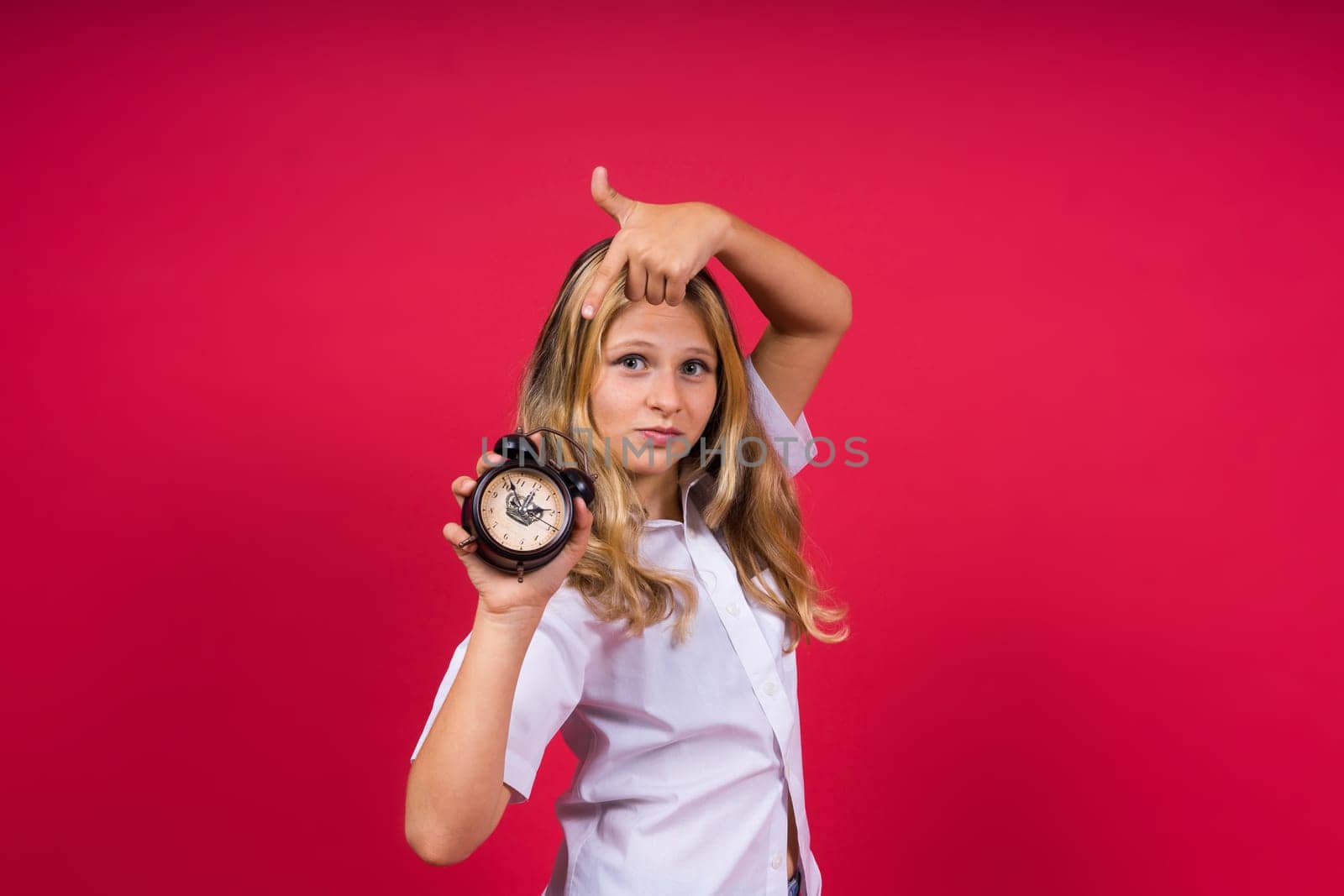 Teen girl 12, 13, 14 years old look at alarm clock. Good morning, checking time. Positive emotions. by Zelenin