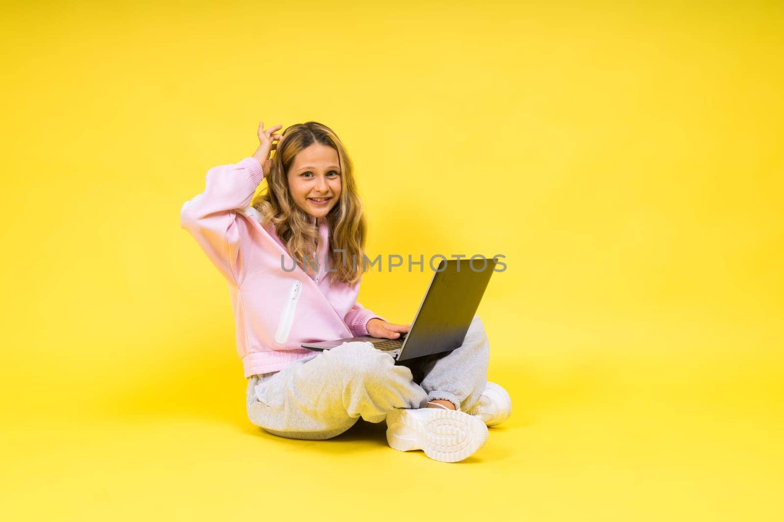 Positive kid sit with laptop read homework wear casual style cloth isolated over yellow background by Zelenin