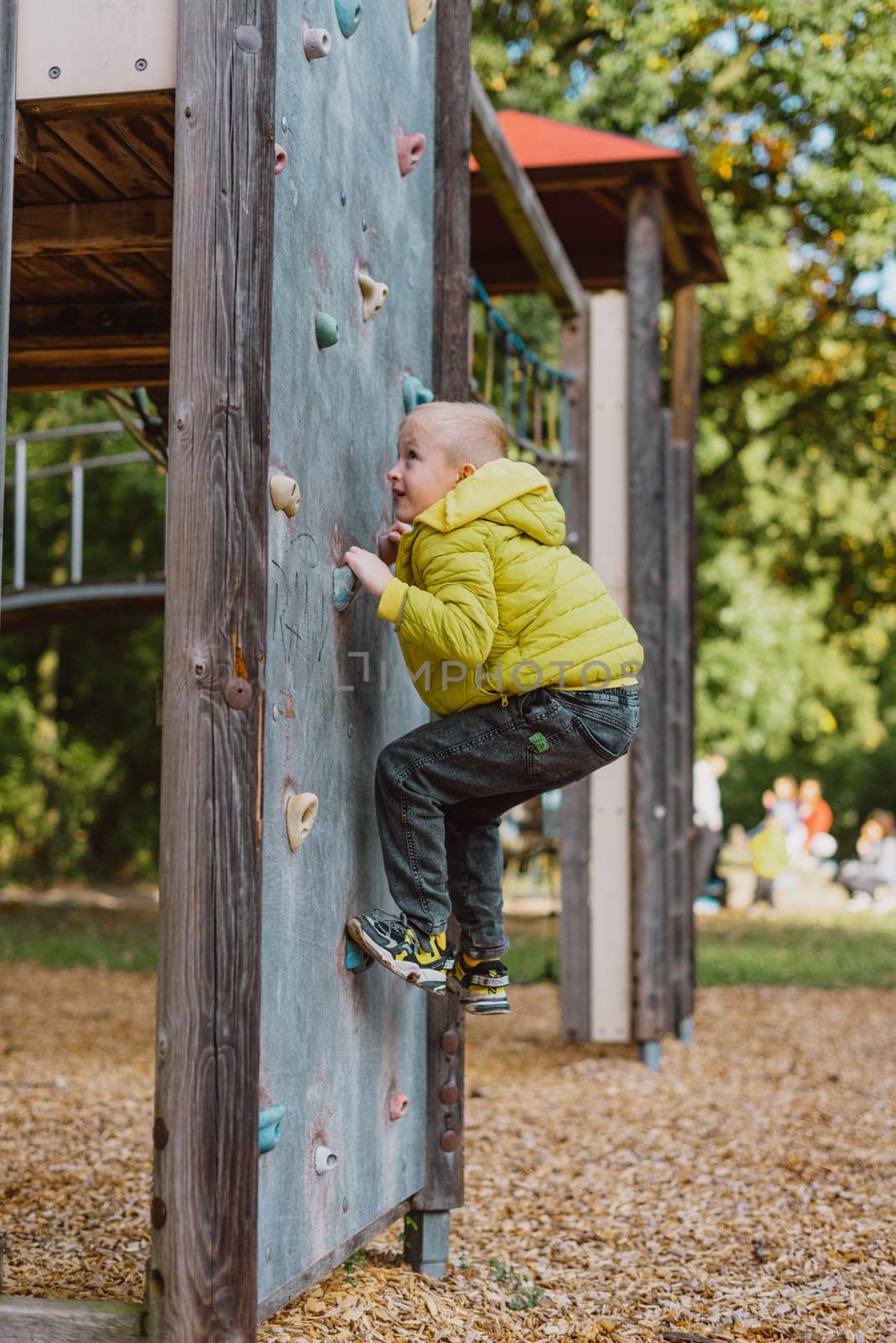 Boy At The Climbing Wall Without A Helmet, Danger At The Climbing Wall. Little Boy Climbing A Rock Wall Indoor by Andrii_Ko