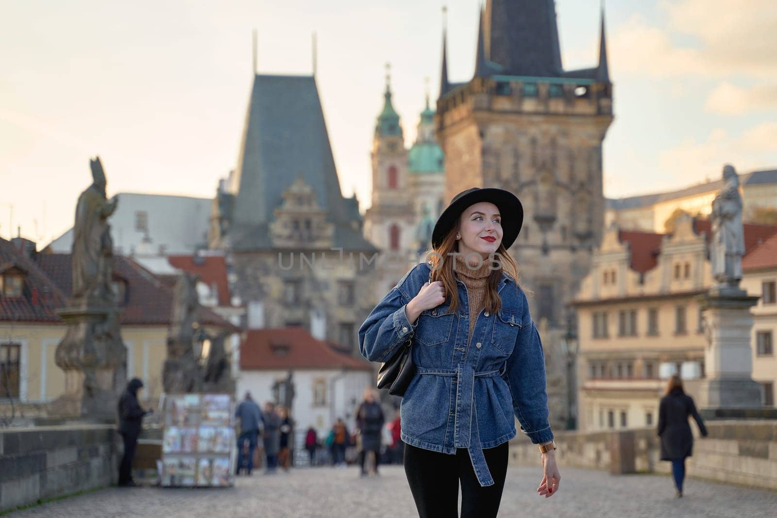 Stylish young beautiful woman earing black hat in Prague on background. Elegant retro lady fine art portrait.