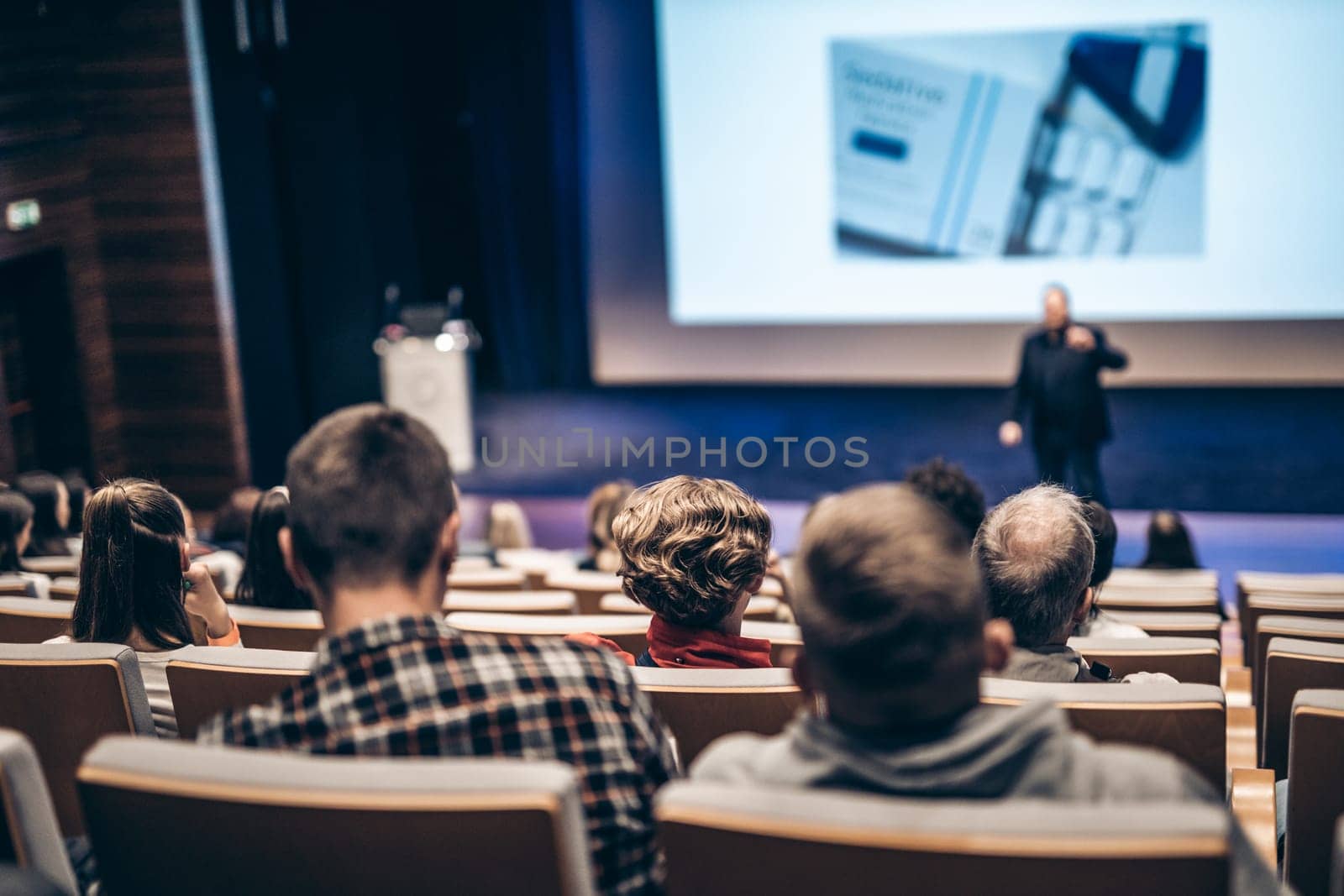 Speaker giving a talk in conference hall at business event. Rear view of unrecognizable people in audience at the conference hall. Business and entrepreneurship concept