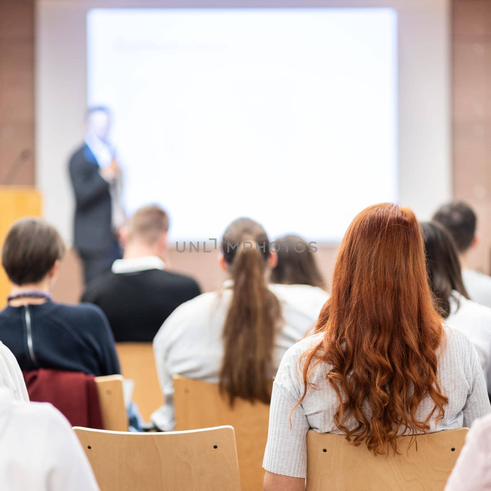 Speaker giving a talk in conference hall at business event. Rear view of unrecognizable people in audience at the conference hall. Business and entrepreneurship concept