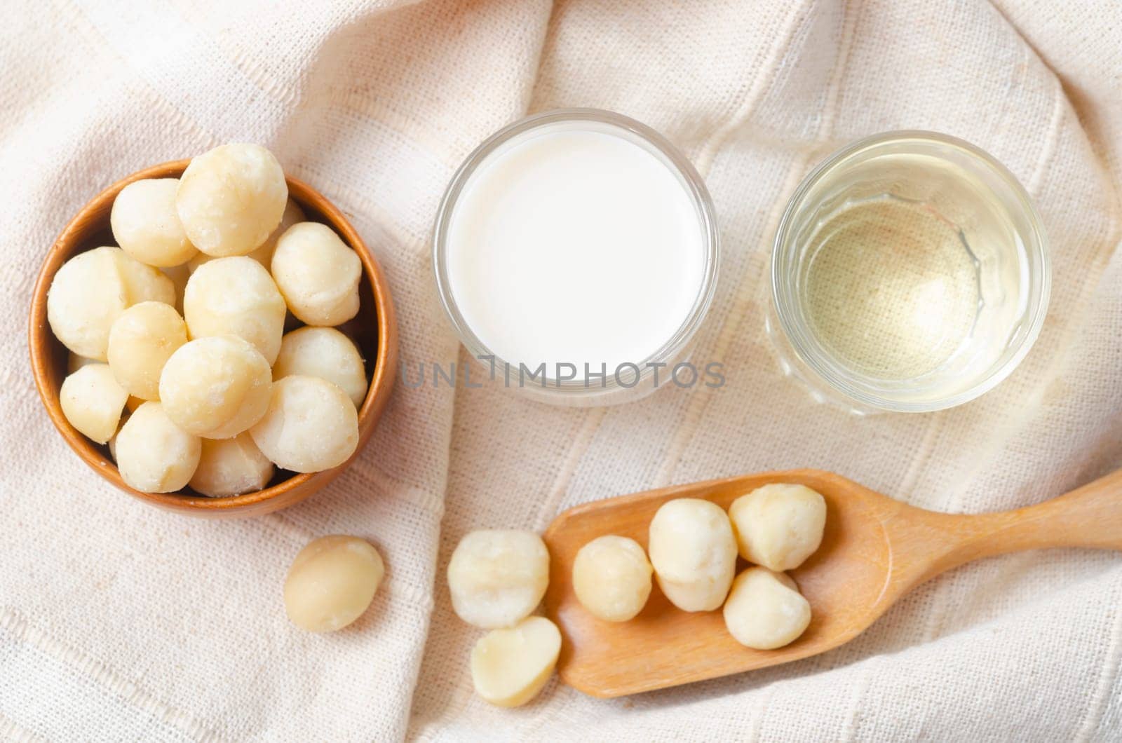 Macadamia milk and Macadamia oil in glass on tablecloth.