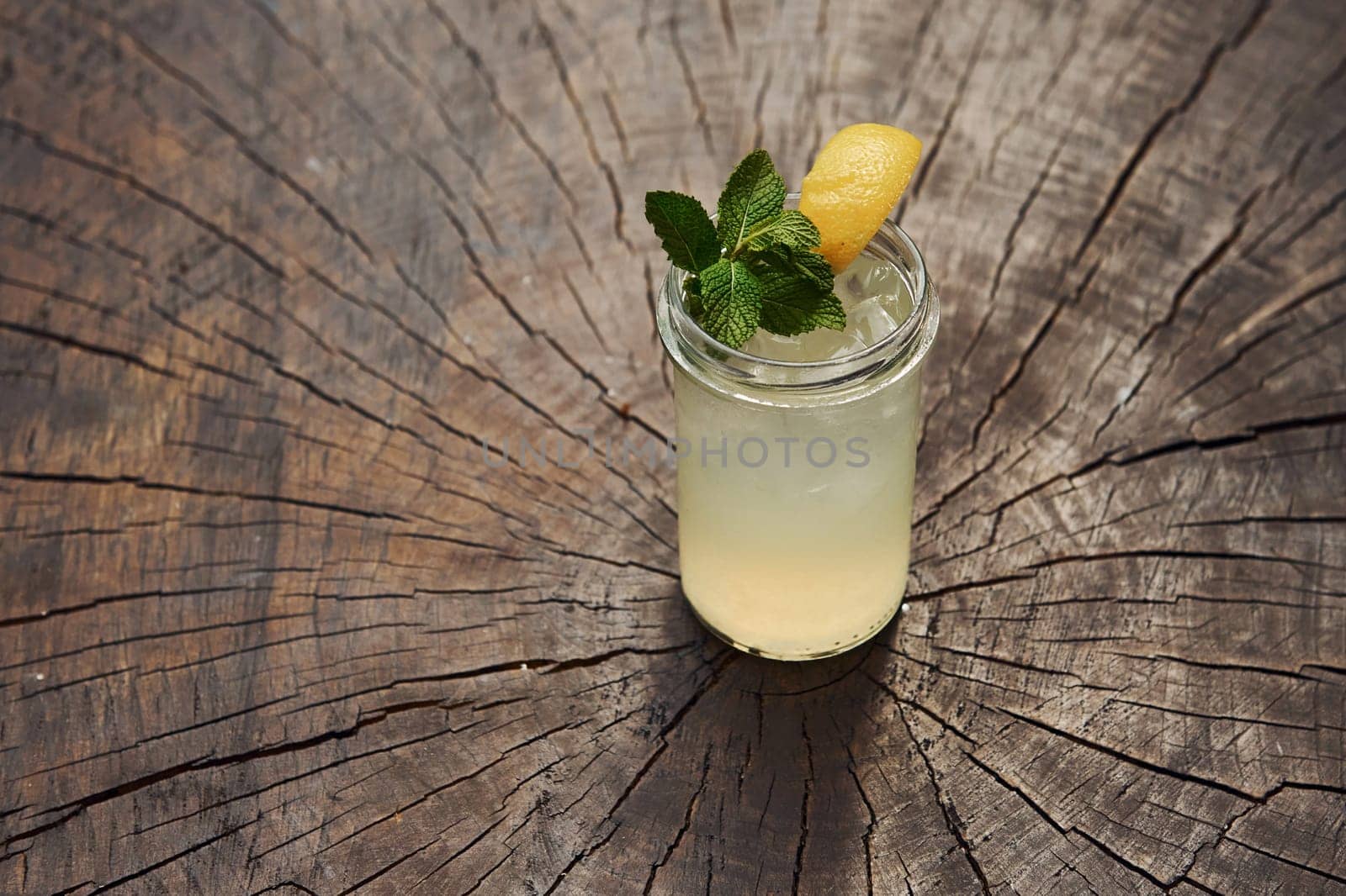 With lemon and mint. Close up view of fresh summer alcoholic cocktail on the wooden table.