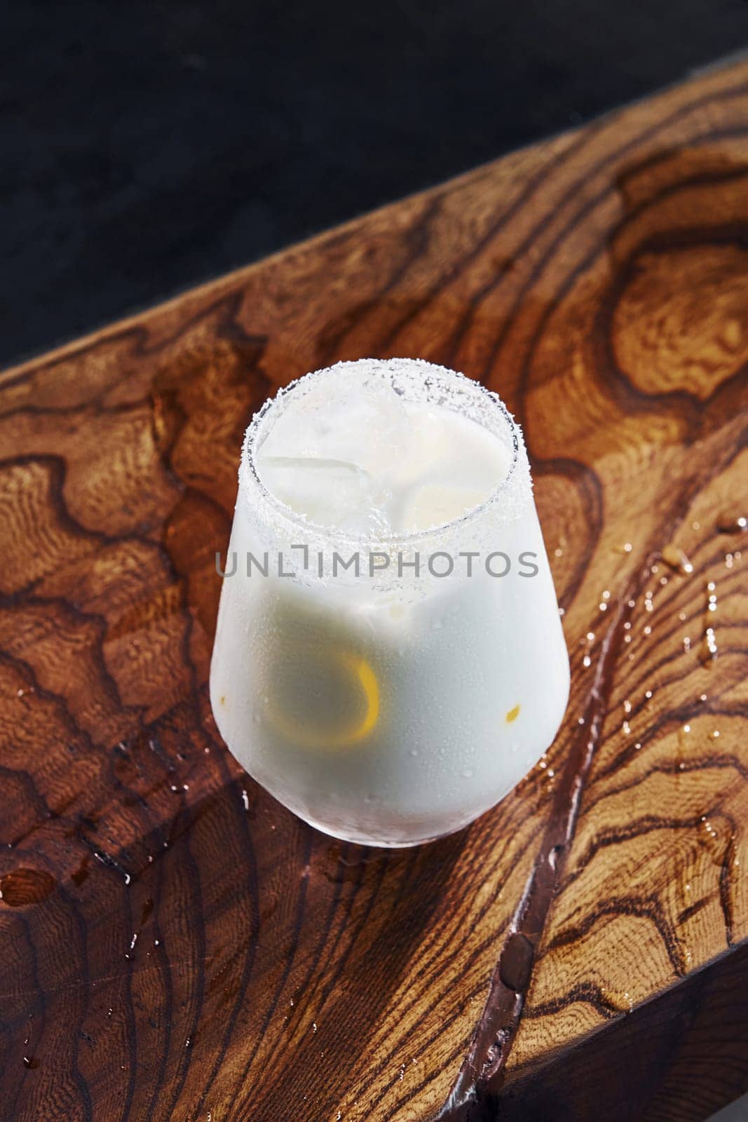 Slice of lemon inside. Close up view of fresh summer cocktail on the wooden table.