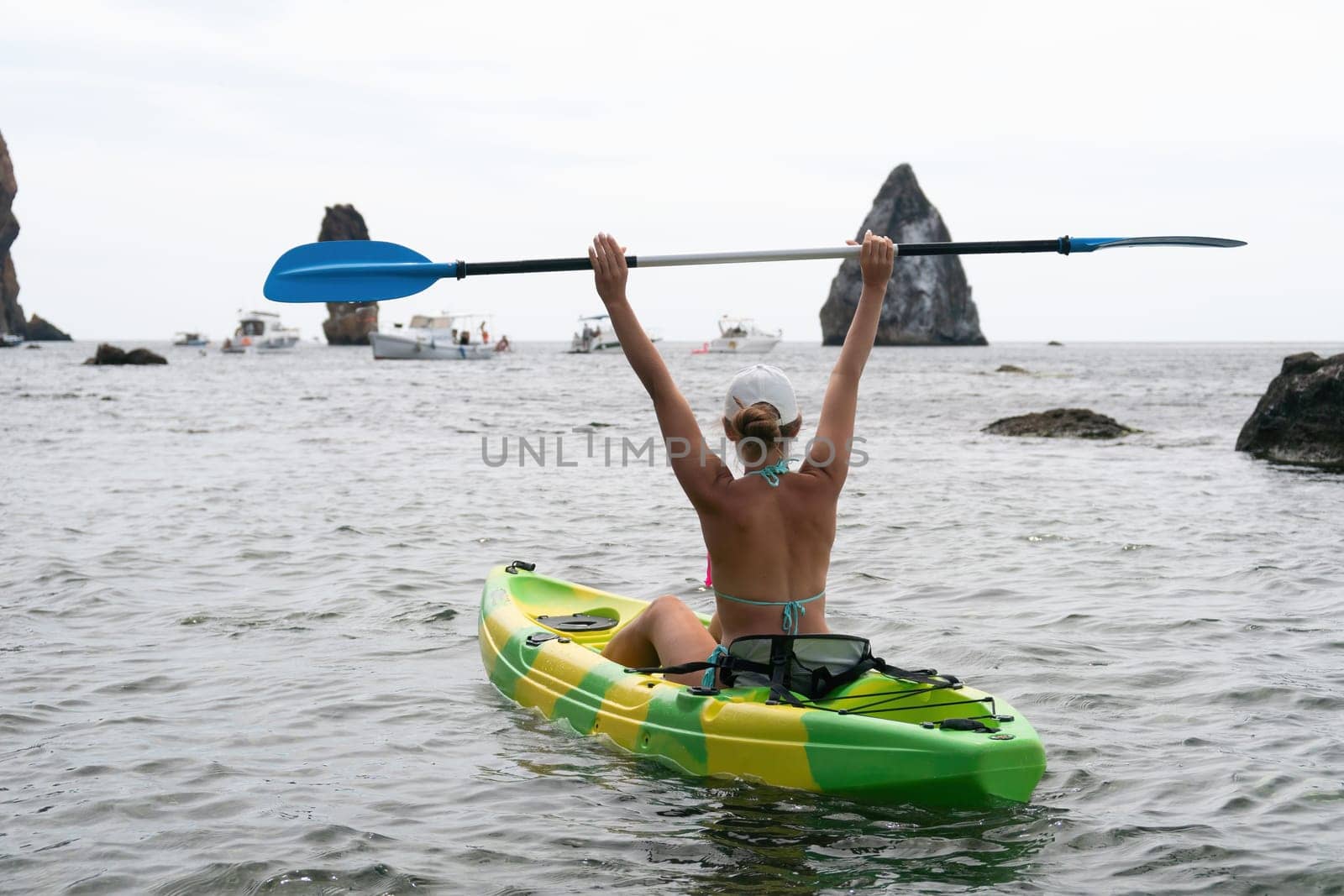 Woman kayak sea. Happy woman kayaks in sea, capturing outdoor memory with happy tourist taking photo. Volcanic mountains surround traveler on adventurous journey in kayak canoe. by panophotograph