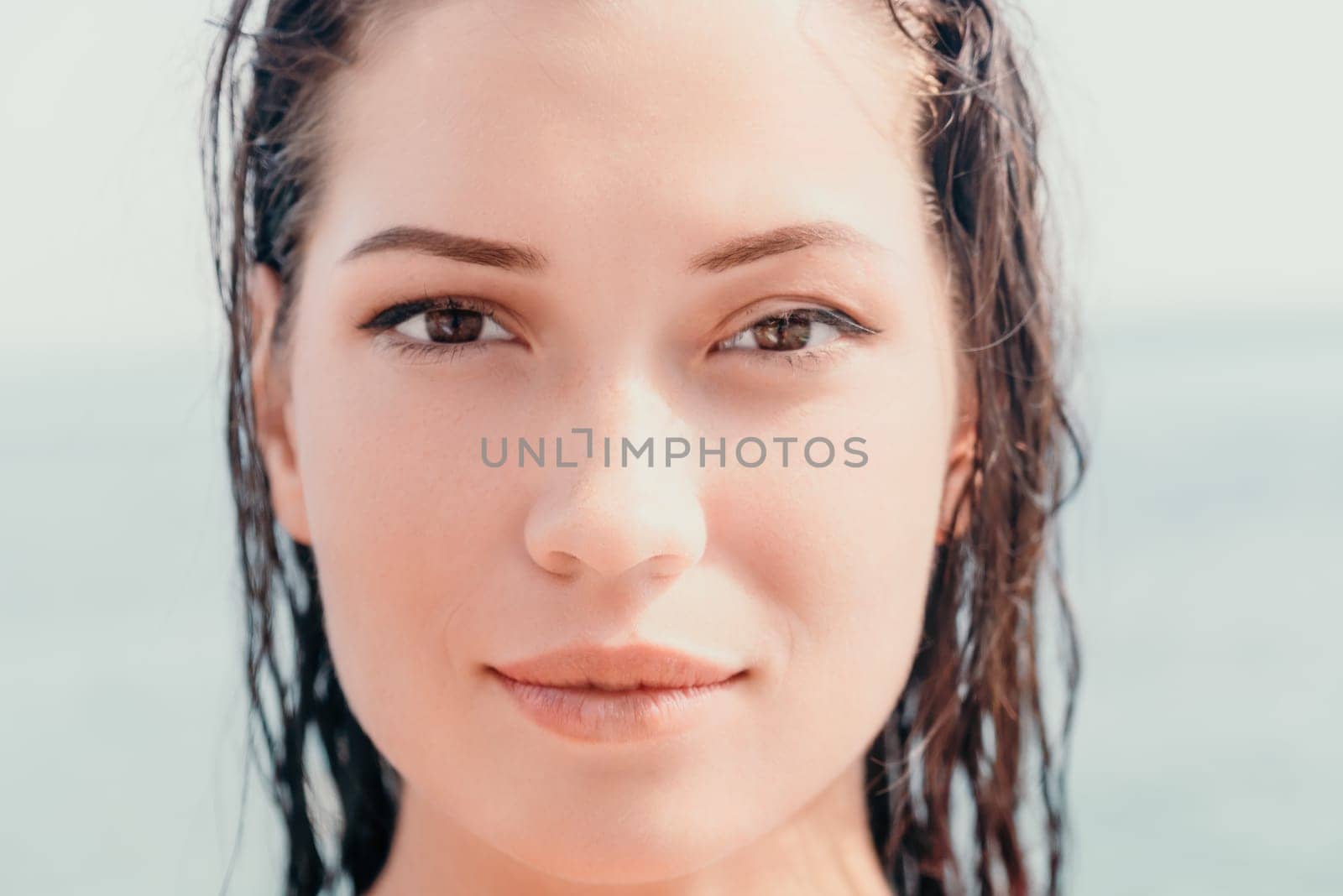 Woman sea sup. Close up portrait of beautiful young caucasian woman with black hair and freckles looking at camera and smiling. Cute woman portrait in a pink bikini posing on sup board in the sea