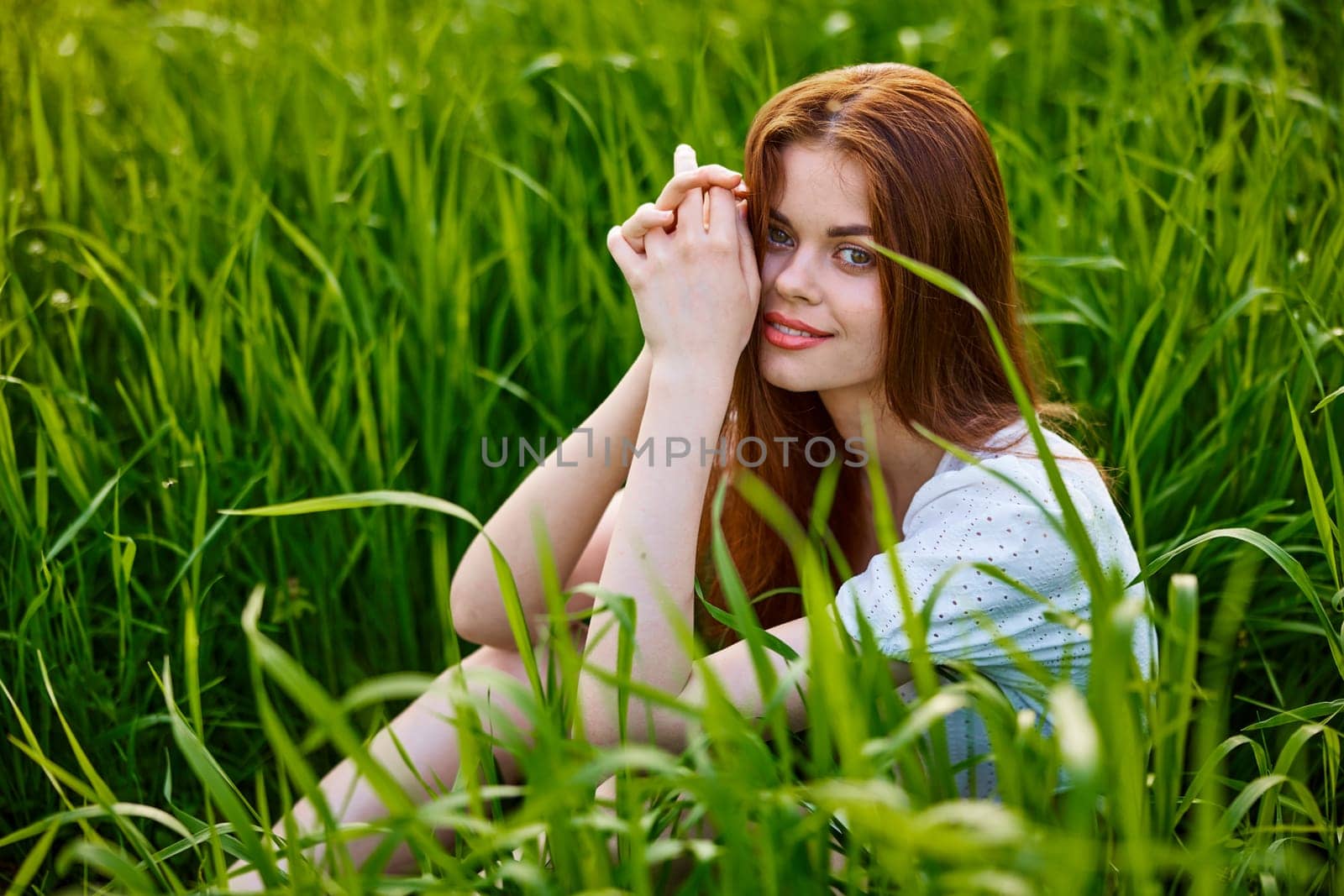 cute woman in summer high grass sits in a light dress. High quality photo