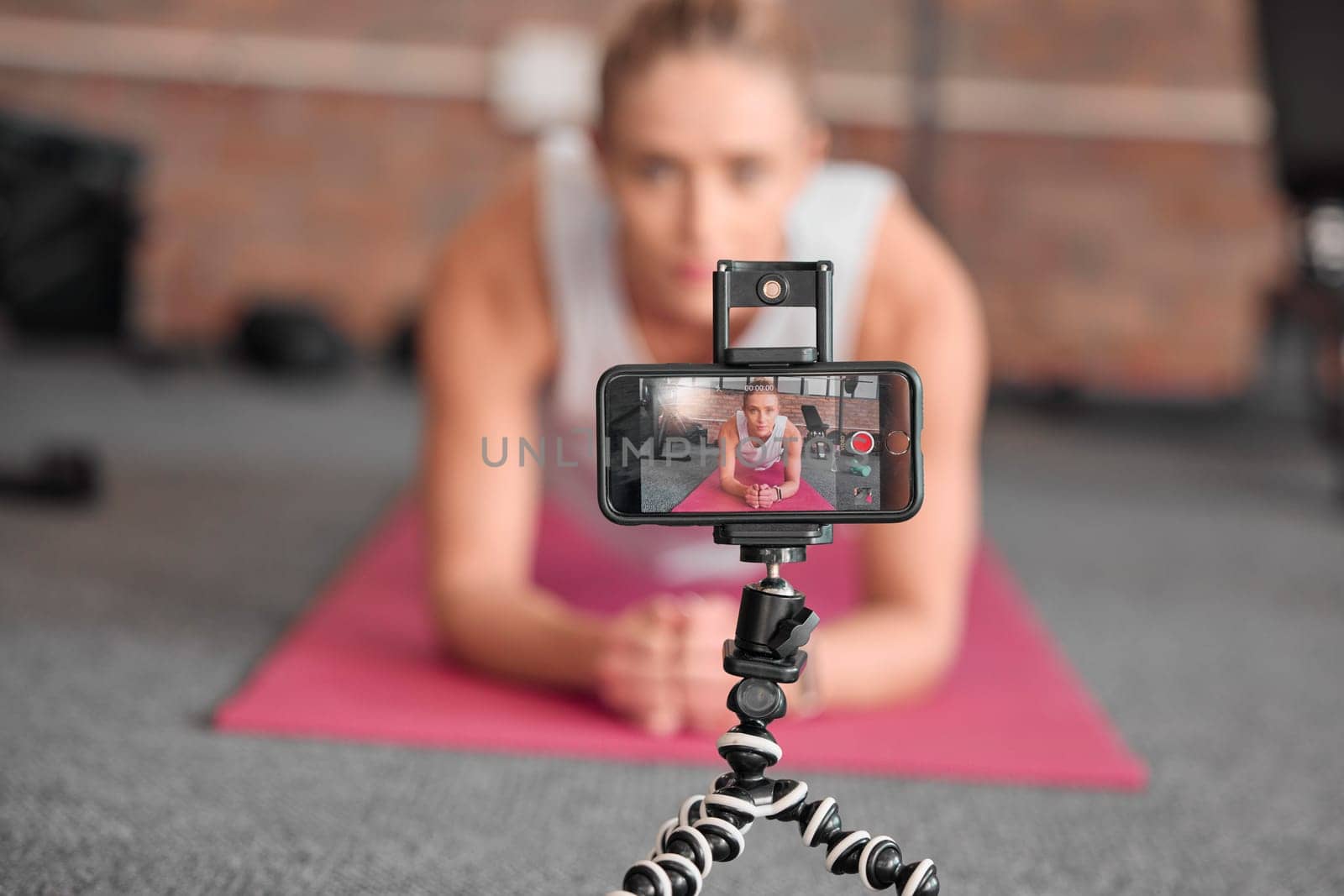 Live streaming, fitness and phone of woman exercise, pilates or workout on social media or video platform on tripod. Gen z athlete, sports influencer or content creator training on smartphone screen by YuriArcurs