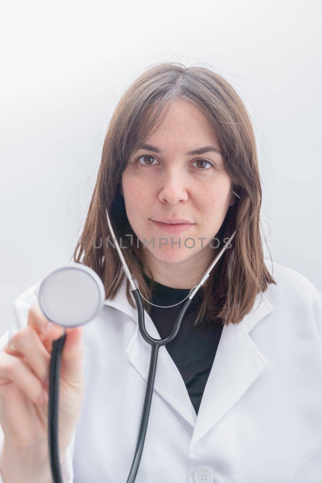 young female doctor in white coat auscultating with stethoscope, isolated on white background and copy space