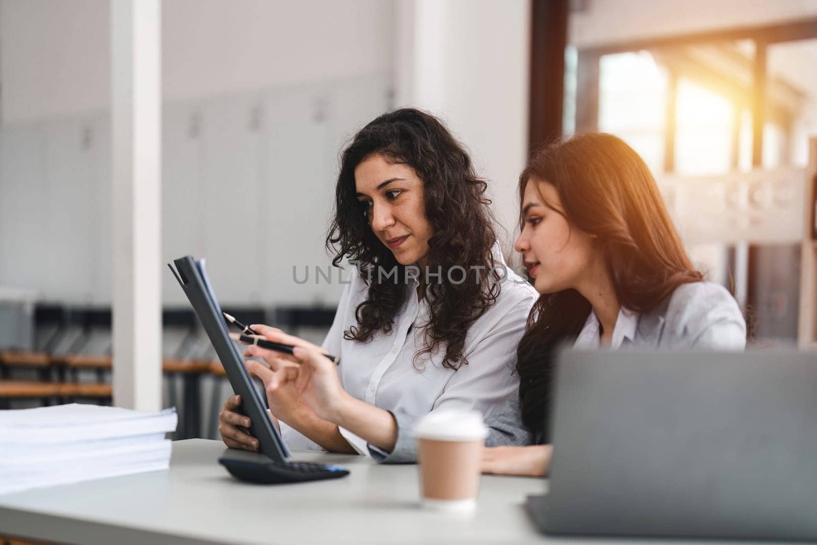 Two smart multiethnic business people working together with laptop while working on project in office.