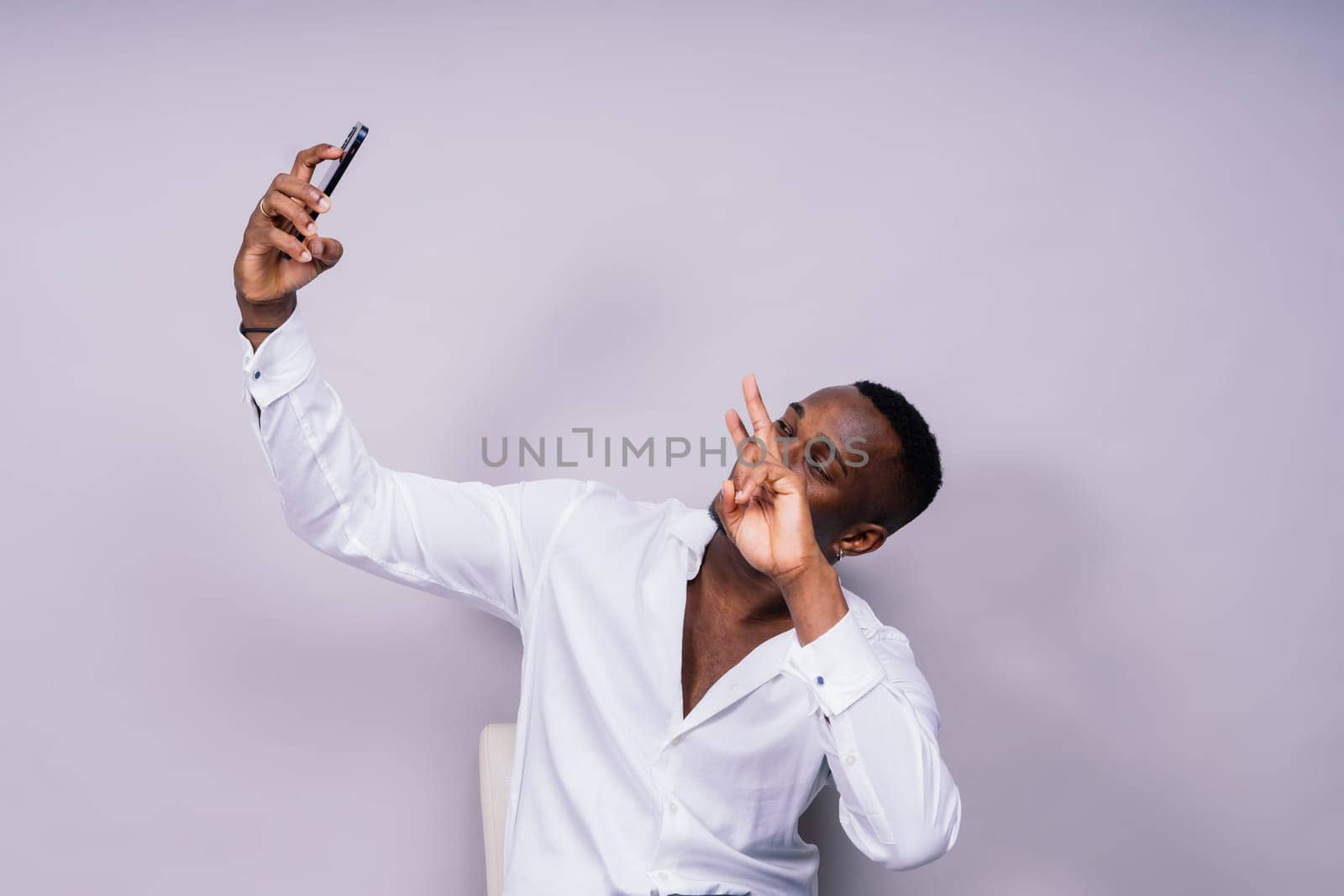 Handsome excited young african business man with mobile phone isolated over gray background by Zelenin