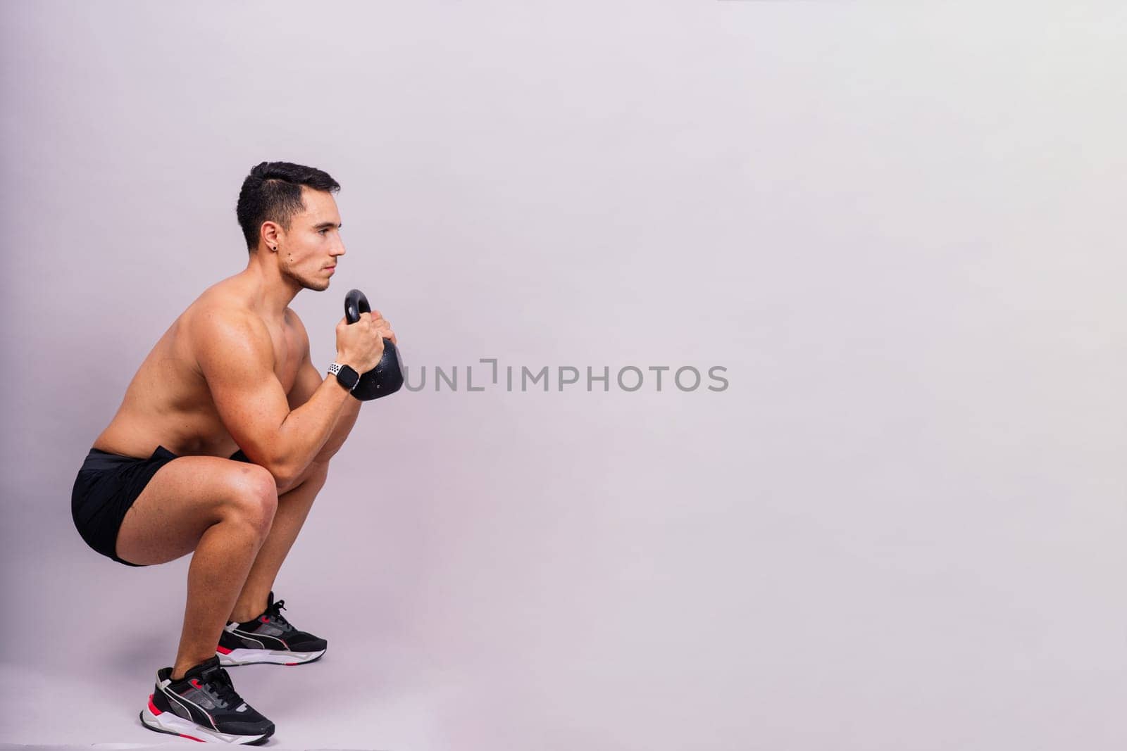 Strong young muscular focused fit man with a big muscles holding heavy kettlebells