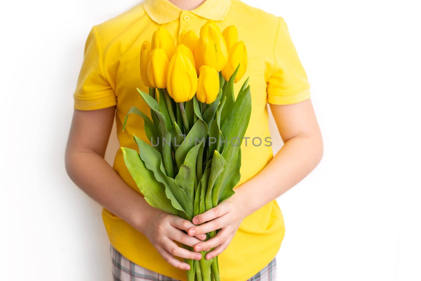 Boy in yellow t-shirt hold a bouquet of yellow tulips, stand on a white background, isolated by Zakharova