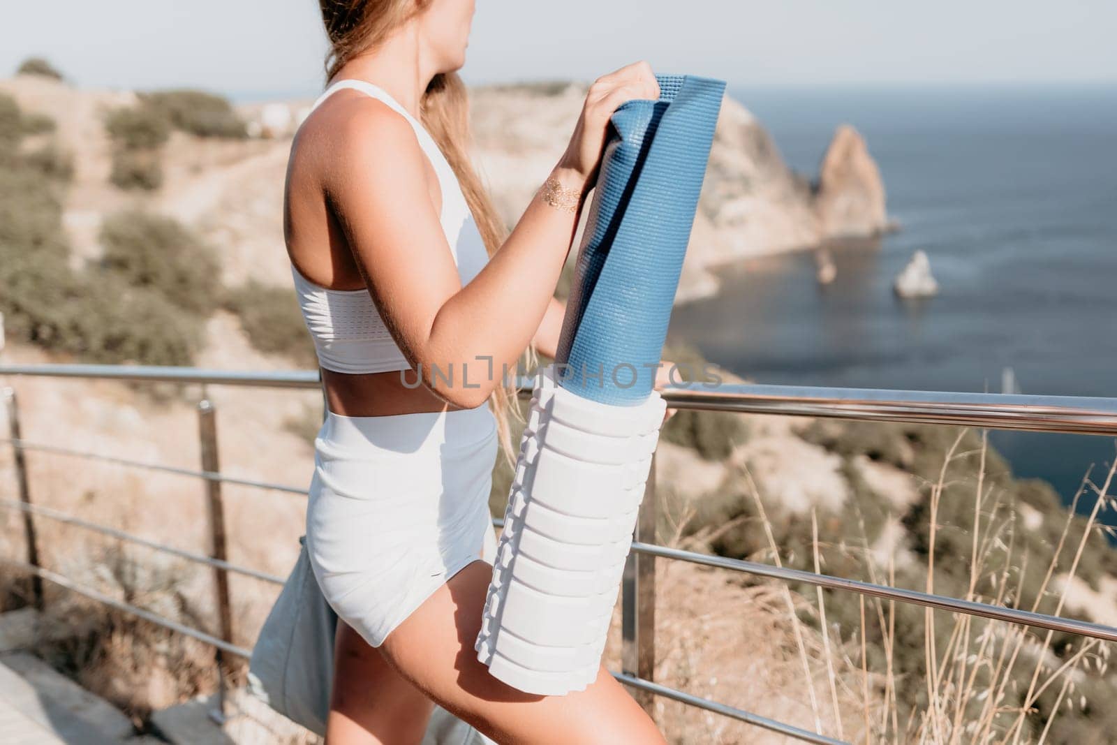 Fitness woman sea. Outdoor workout on yoga mat in park near to ocean beach. Female fitness pilates yoga routine concept. Healthy lifestyle. Happy fit woman exercising with rubber band in park.