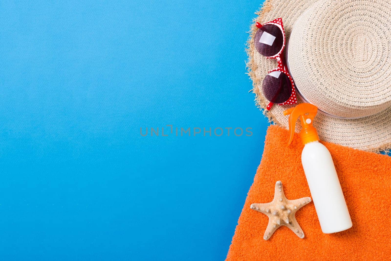 Summer beach flat lay accessories. Sunscreen bottle cream, towel and seashells on colored Background. Travel holiday concept with copy space.