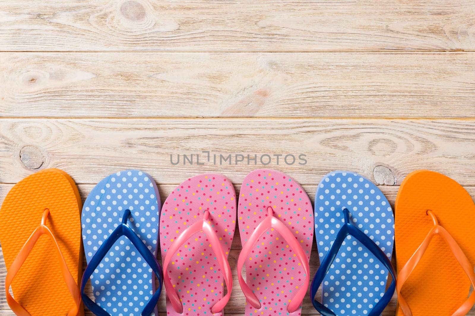 a lot of flip flop colored sandals, summer vacation on wooden background, copy space top view.