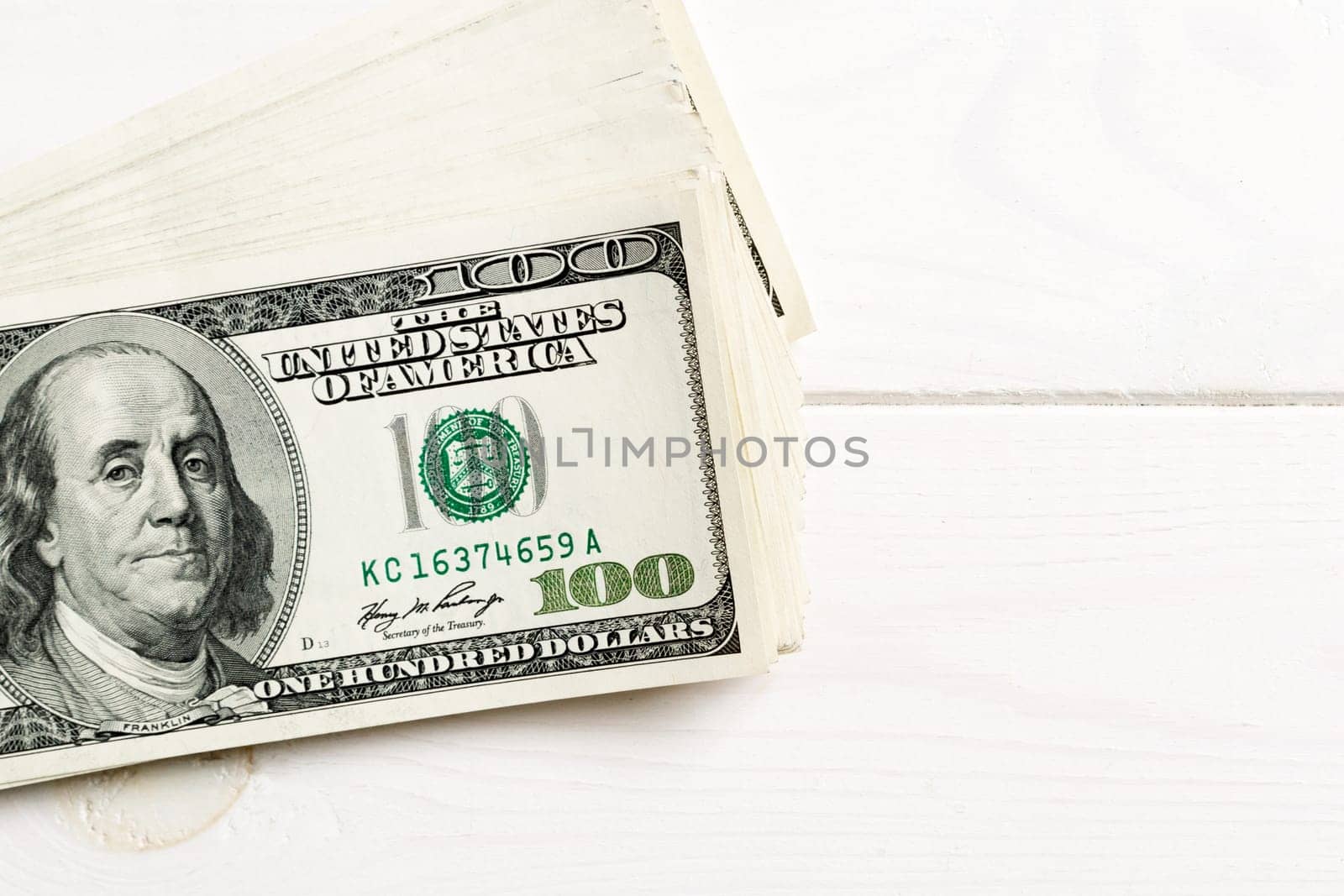 Stack of 100 dollar banknotes on wooden background. Top view of financial concept with empty space for your design.