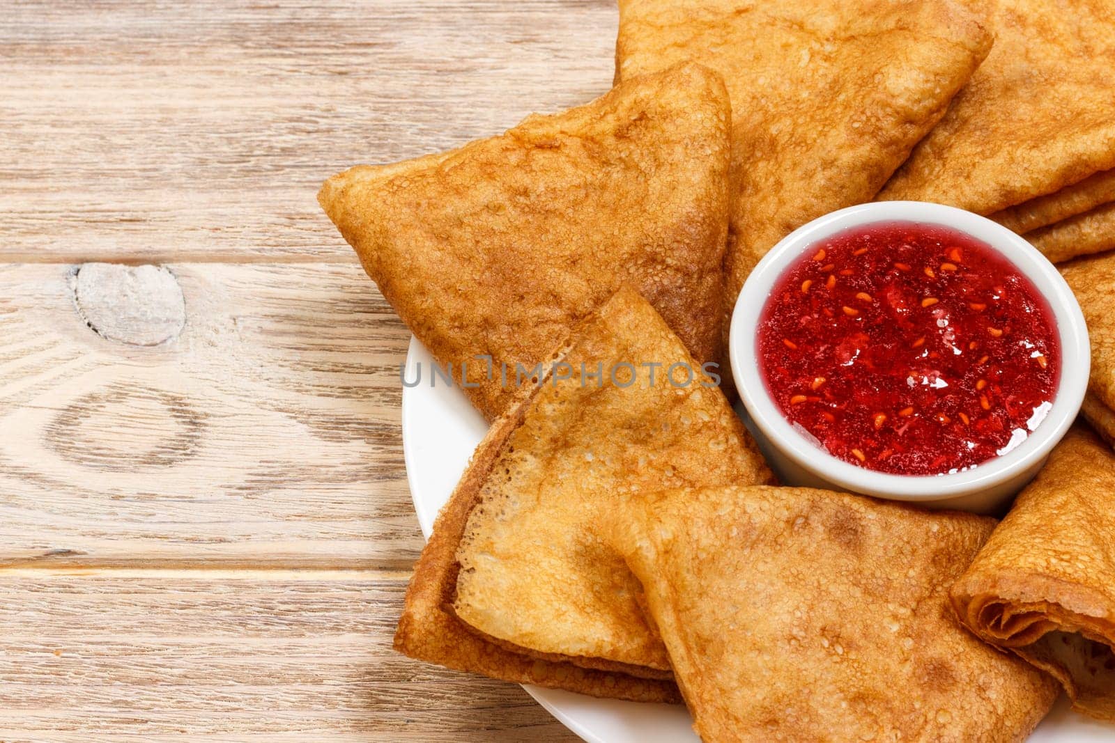 Crepes on a plate with raspberry jam for a breakfast top view with copy space.