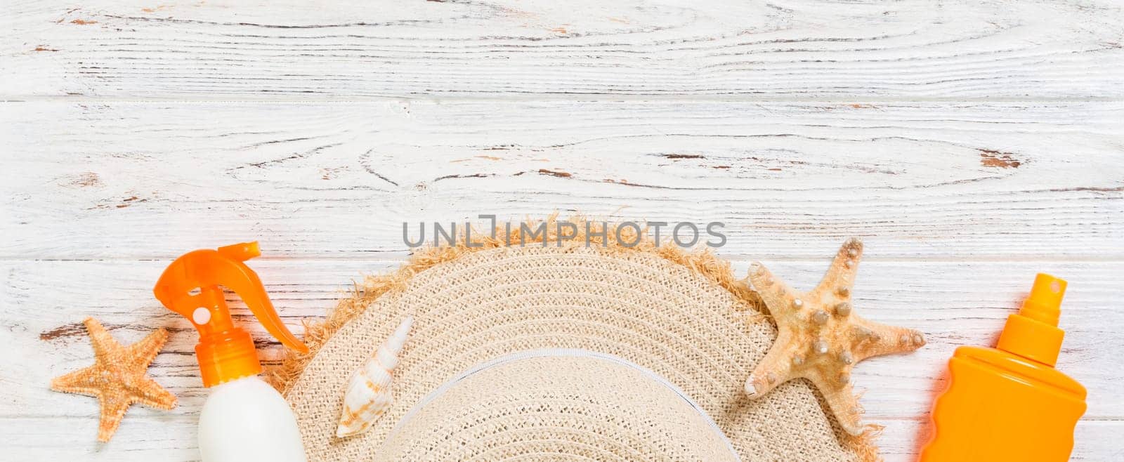 Sunscreen bottles with starfish and sunhat on white wooden table banner with copy space. Travel healthcare accessories top view.