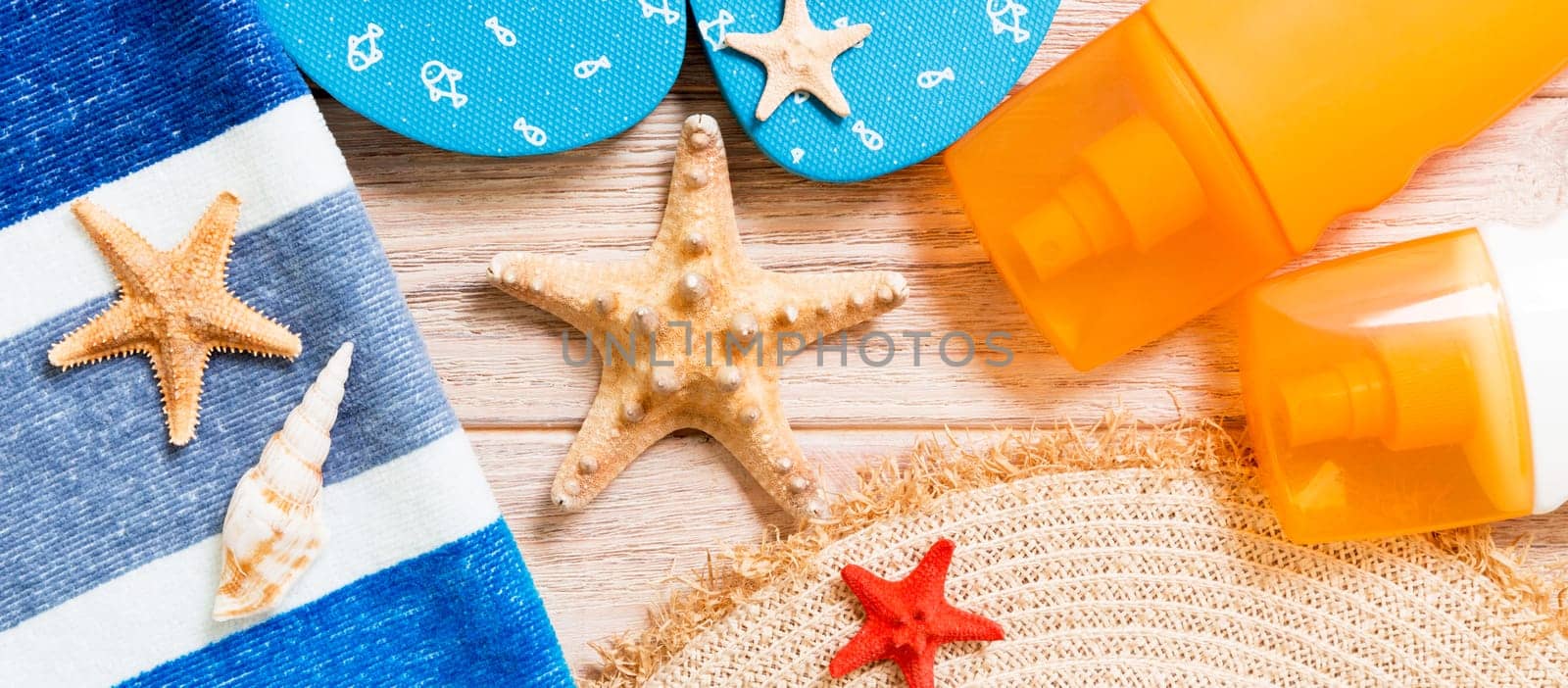 flip flops, straw hat, starfish, sunscreen bottle, body lotion spray on wooden background top view banner . flat lay summer beach sea accessories background, travel concept.