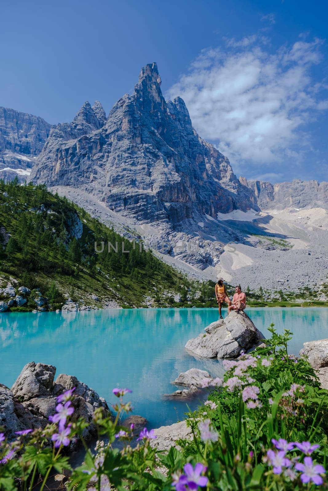 Couple of men and women visiting Lago di Sorapis in the Italian Dolomites, milky blue lake Lago di Sorapis, Lake Sorapis, Dolomites, Italy.