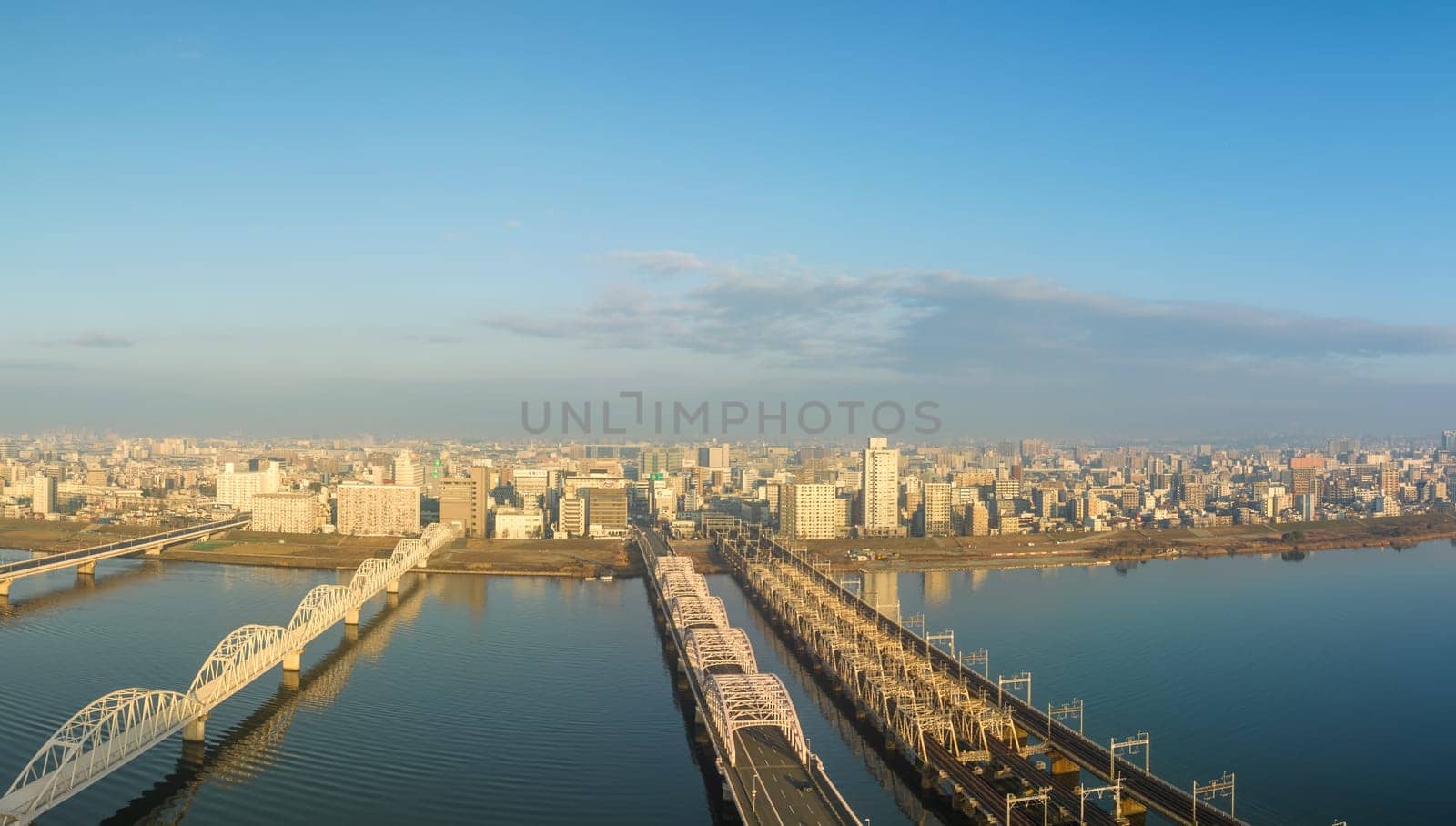 Vehicle bridge next to train bridge over wide river next to city after sunrise. High quality photo