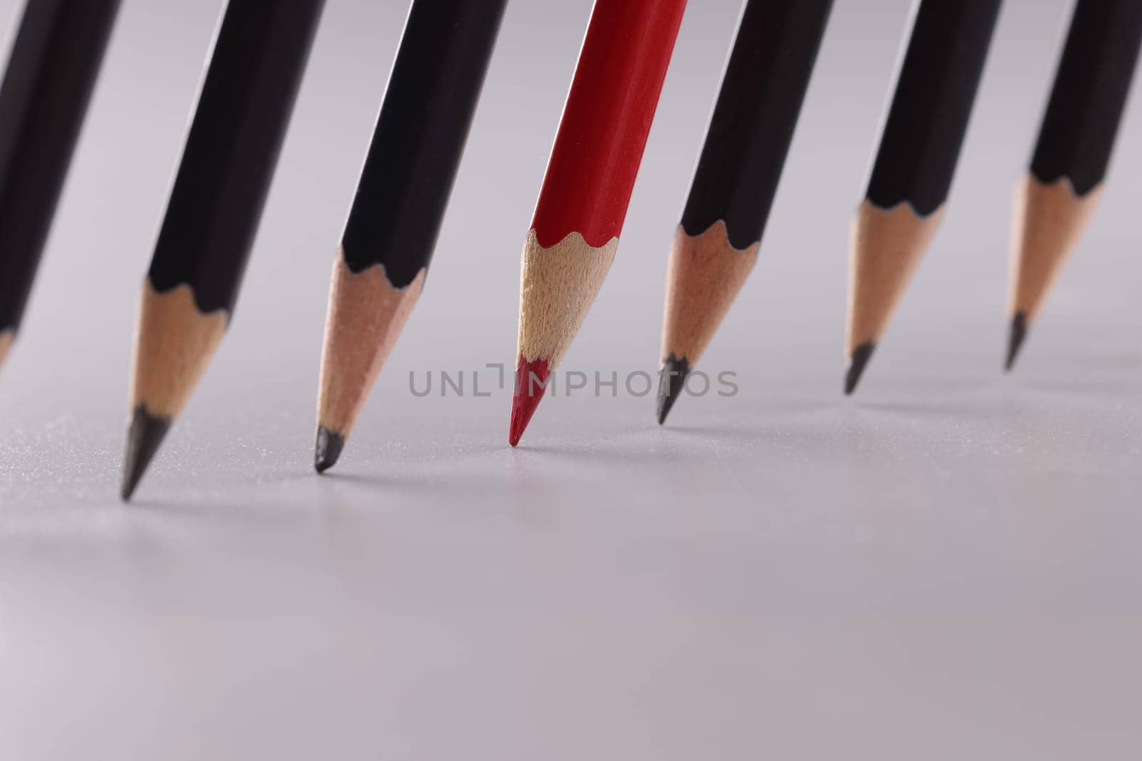 Bright red pencil stands out from identical black pencils by kuprevich